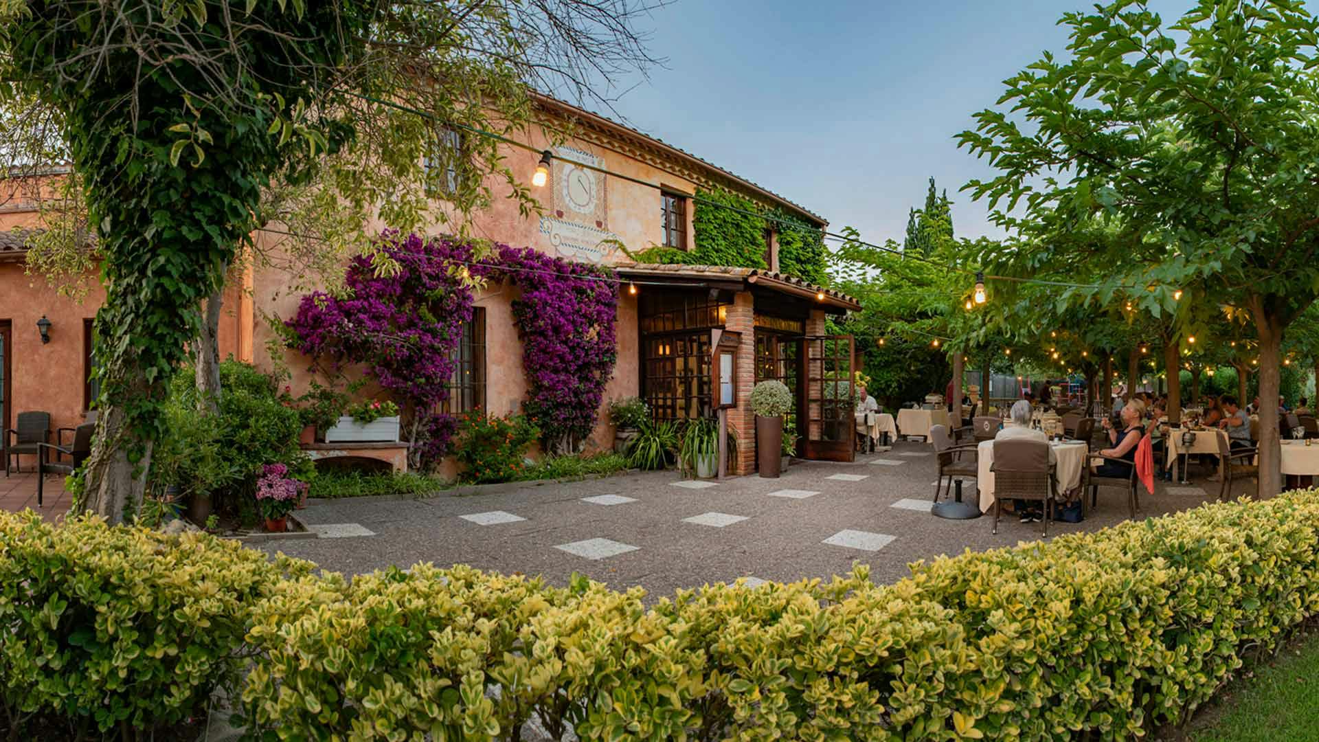 Outdoor dining area of a restaurant in Lloret de Mar, featuring a garden with colorful flowers.