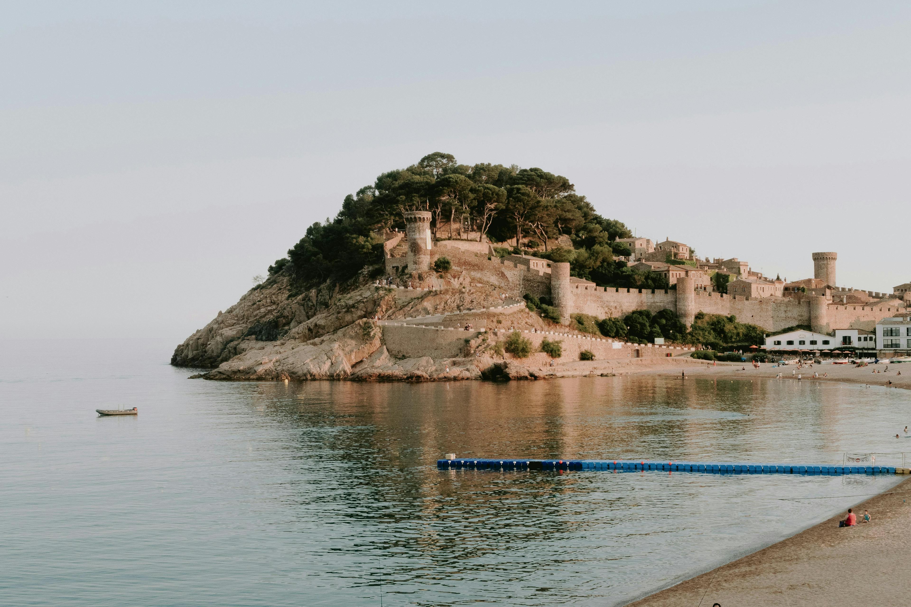 A beach in Lloret de Mar with a castle overlooking the waters.