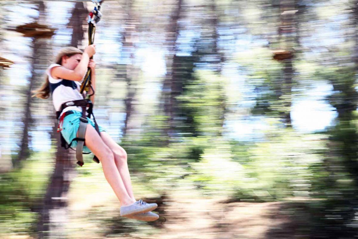 A young girl happily glides along a zipline. 