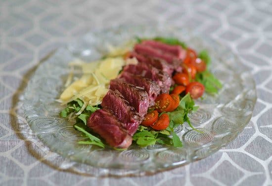 Steak with tomatoes and cheese on a plate, served at a restaurant in Lloret de Mar.