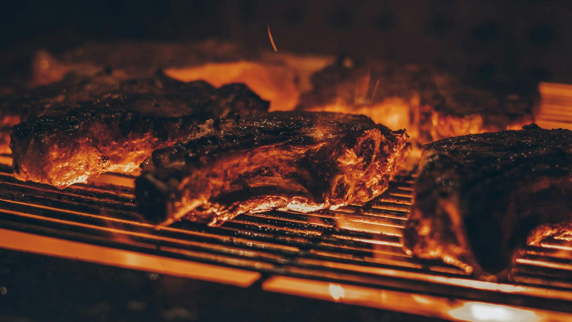 Flames engulfing steaks on a grill at La Parrilla, Lloret de Mar.