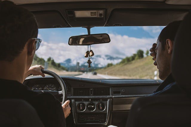 Two men sitting in the front seats of a car in Spain. 