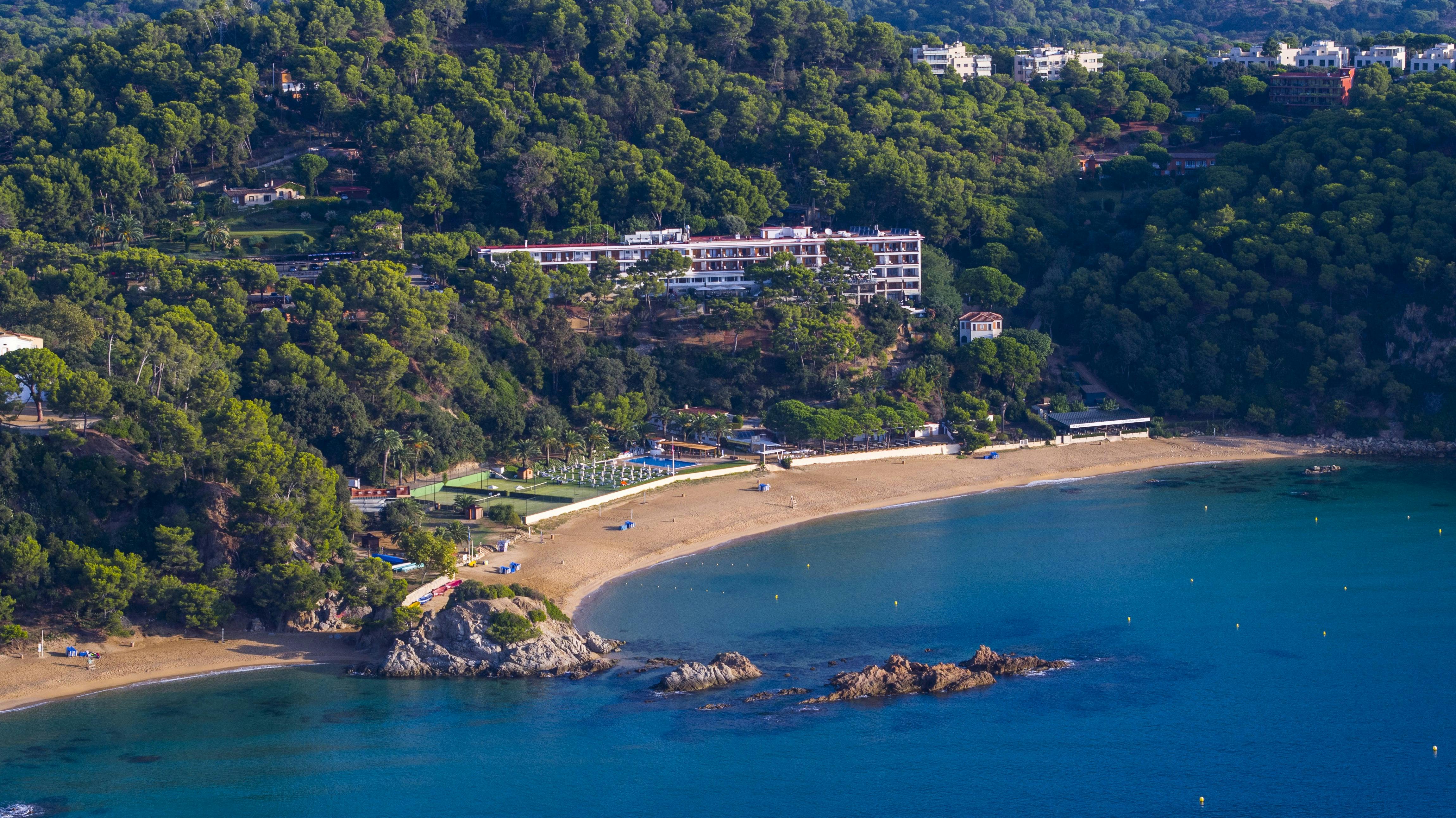 A beach setting with a hotel tucked among some trees, providing a calm getaway by the ocean.