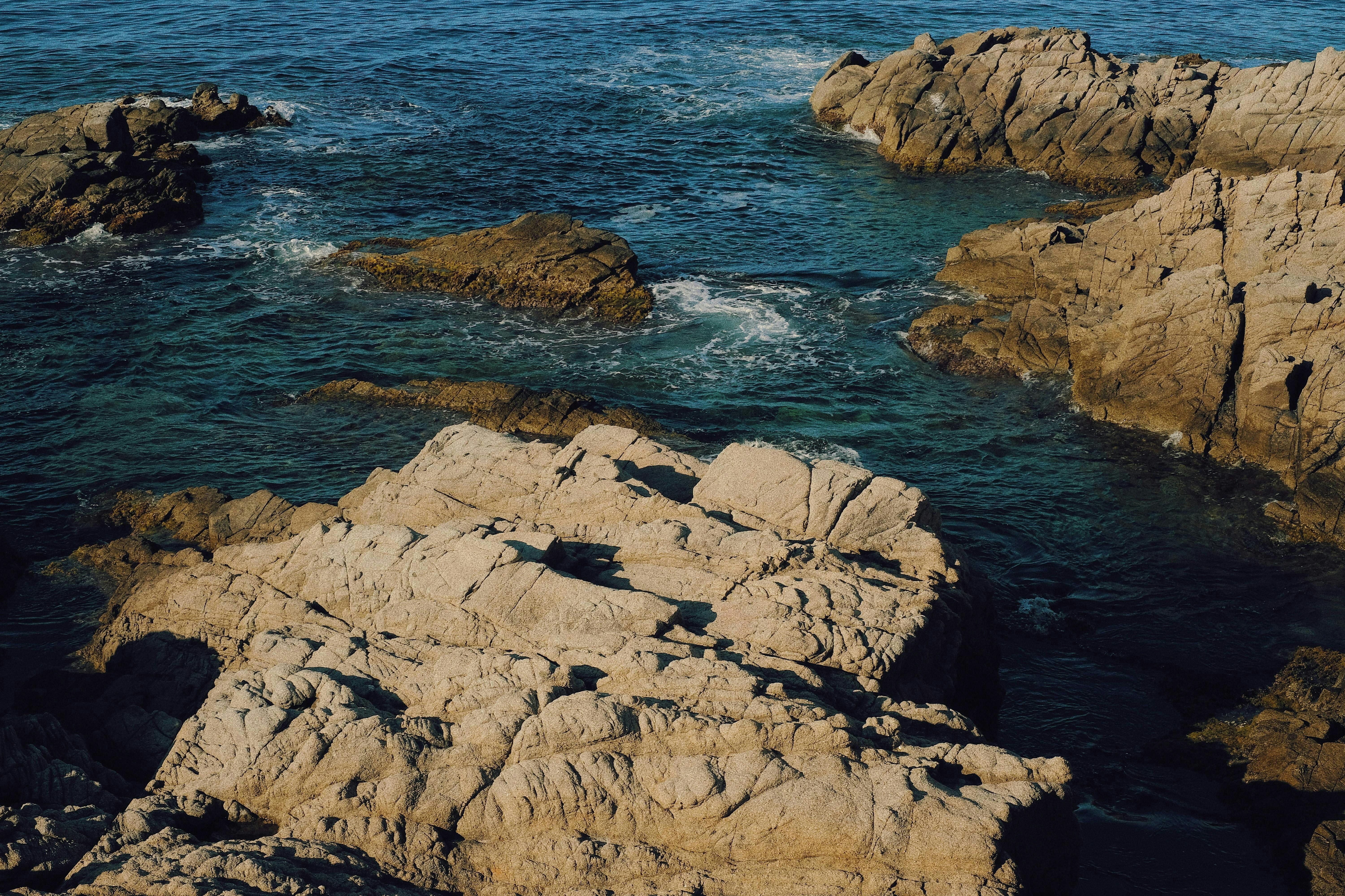 A serene ocean with rocks scattered along the shore.