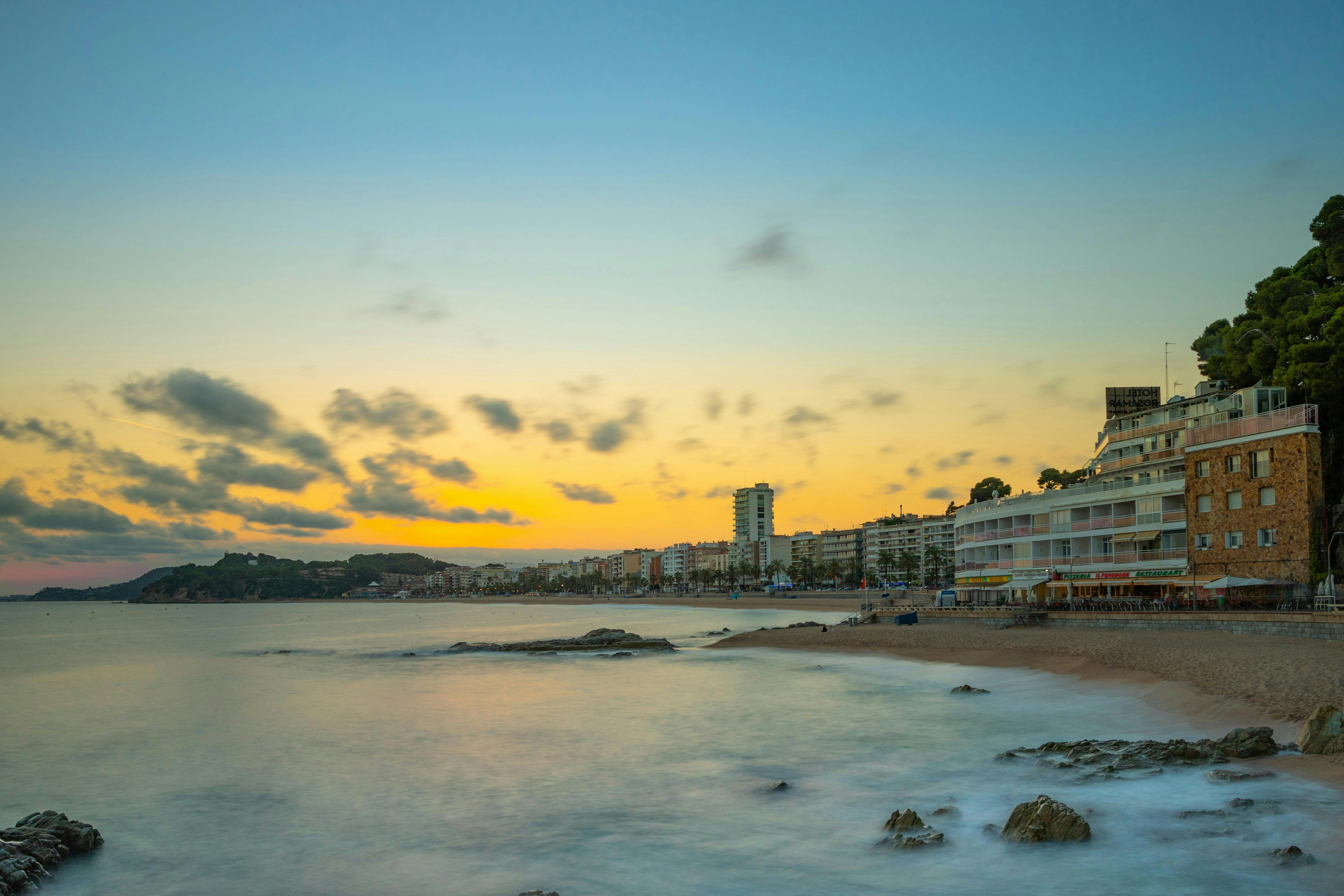 Sunset over ocean and beach buildings in Lloret de Mar. 