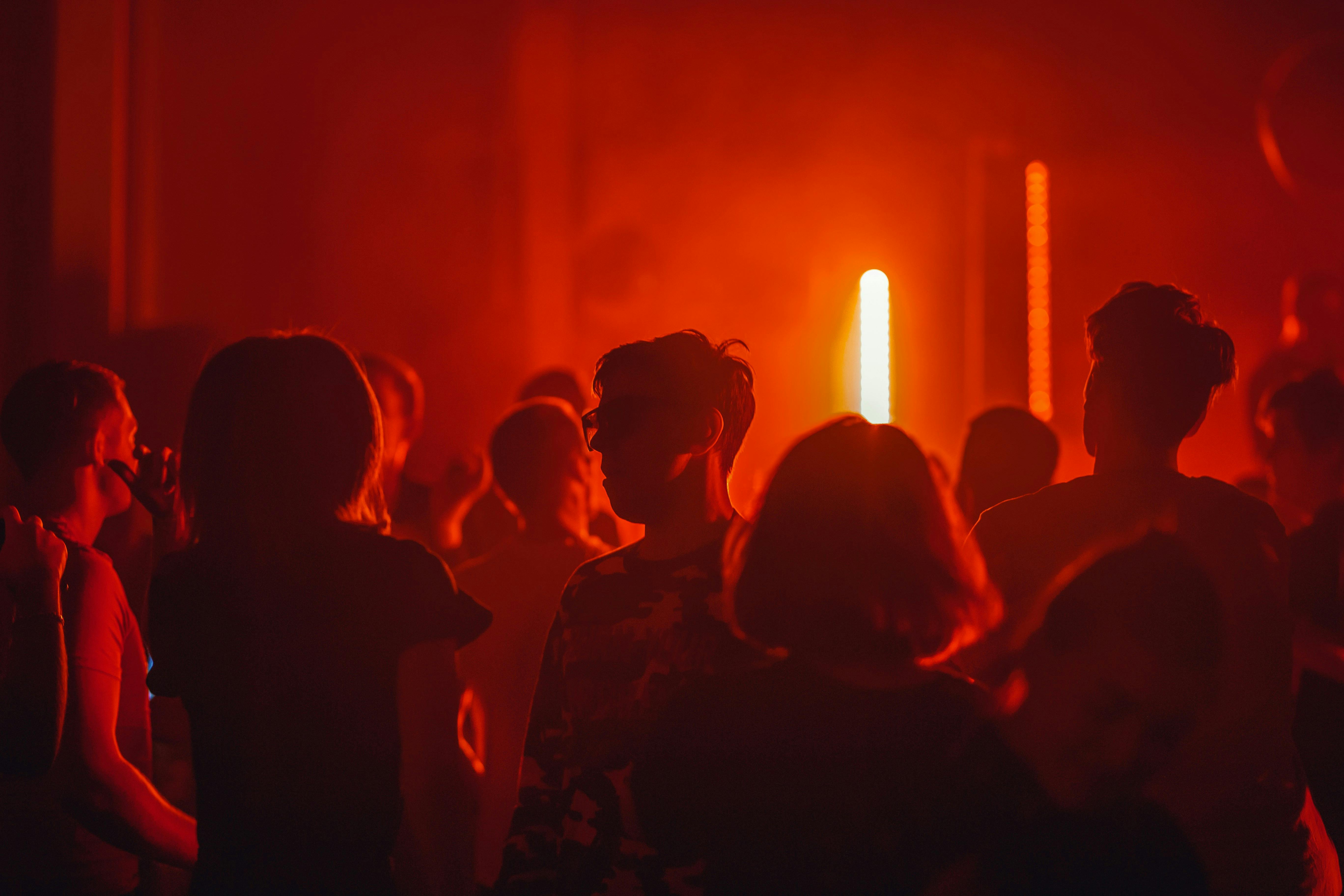 People in a dimly lit room with red lights. 