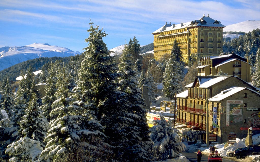 Un pueblo de montaña nevado con un gran edificio al fondo.