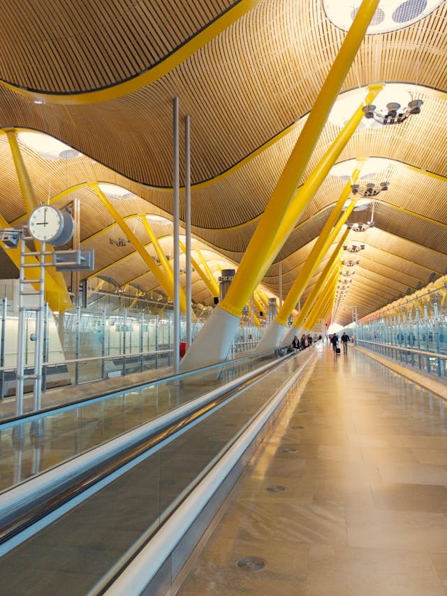 A long walkway at Madrid-Barajas airport with people walking on it.