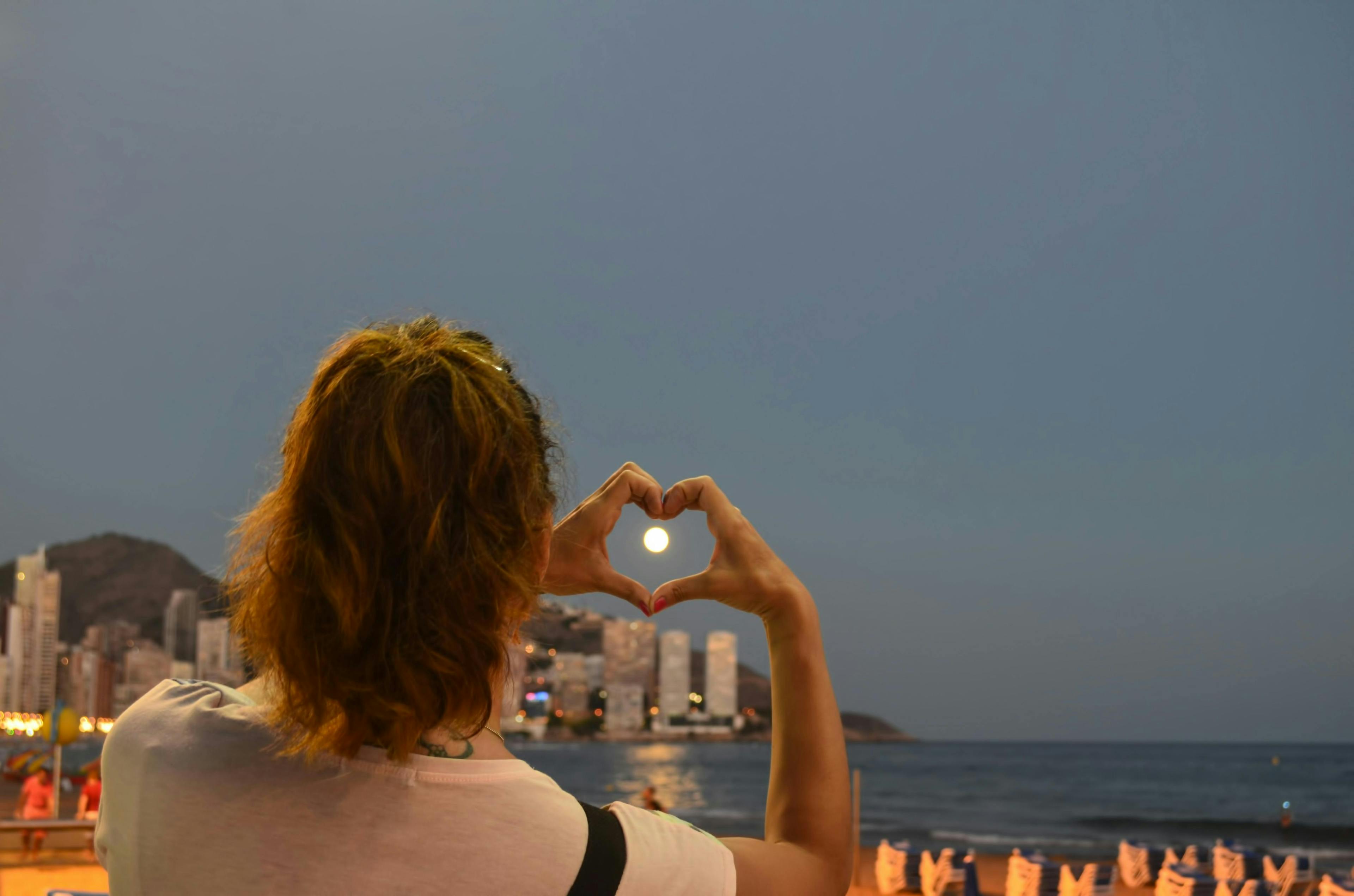 Una mujer en la playa de Benidorm, formando un corazón con sus manos.