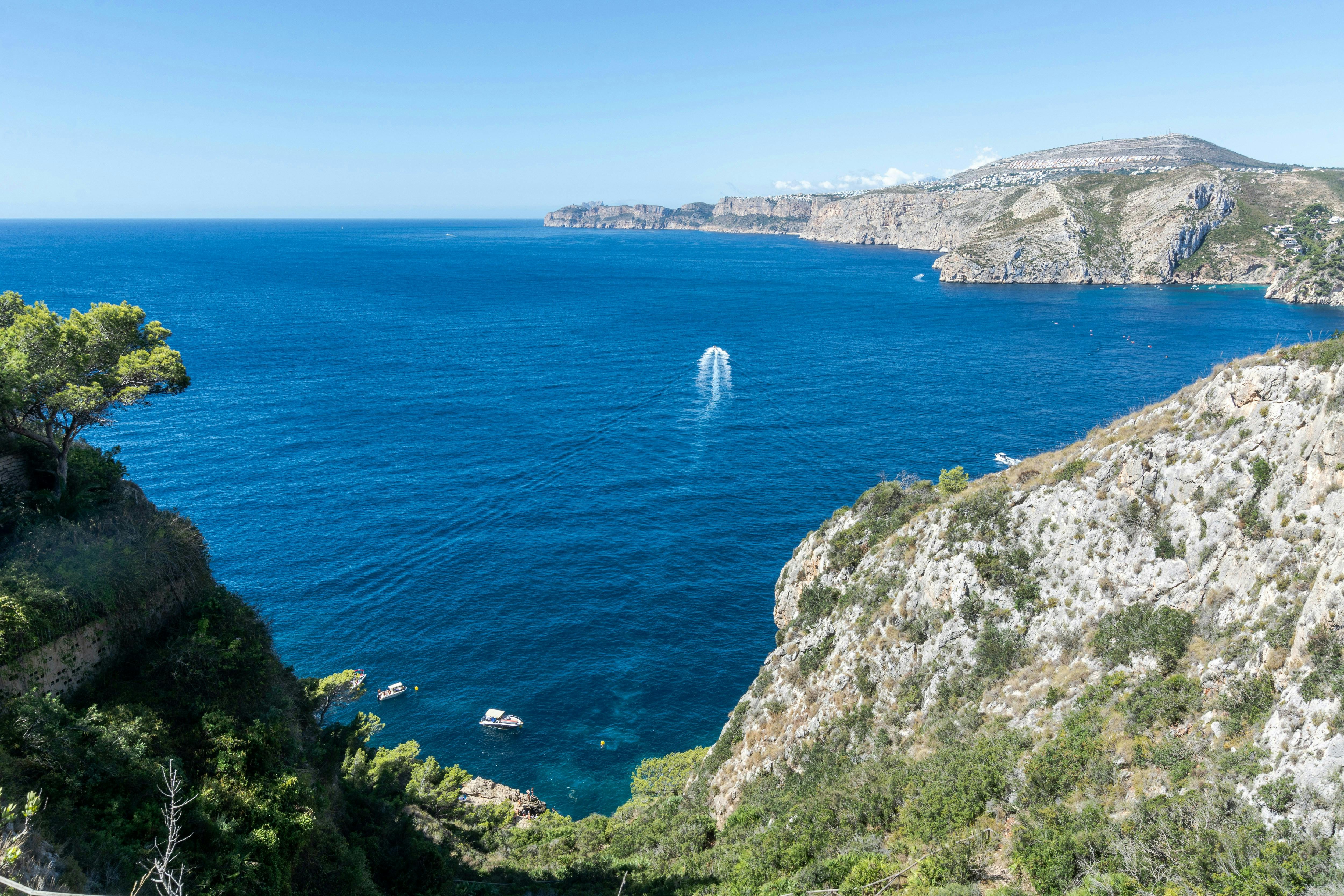 Un bateau naviguant près de la côte de Jávea dans l'eau.