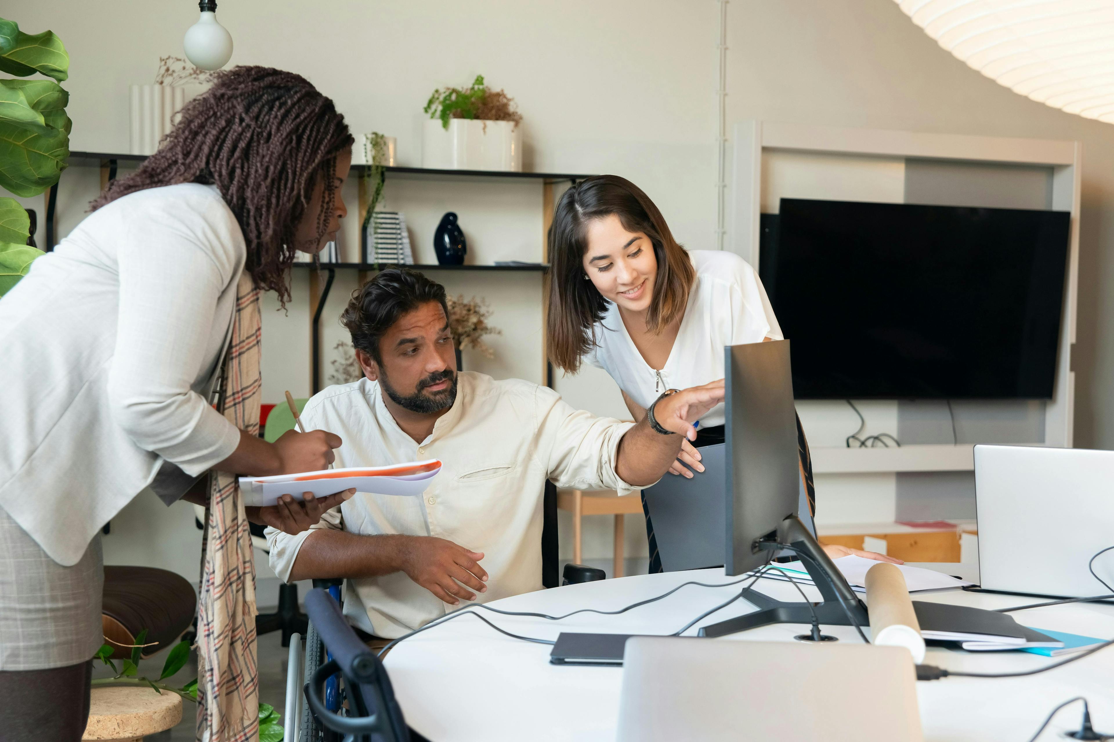 Three staff members working together on a computer in a travel agency office