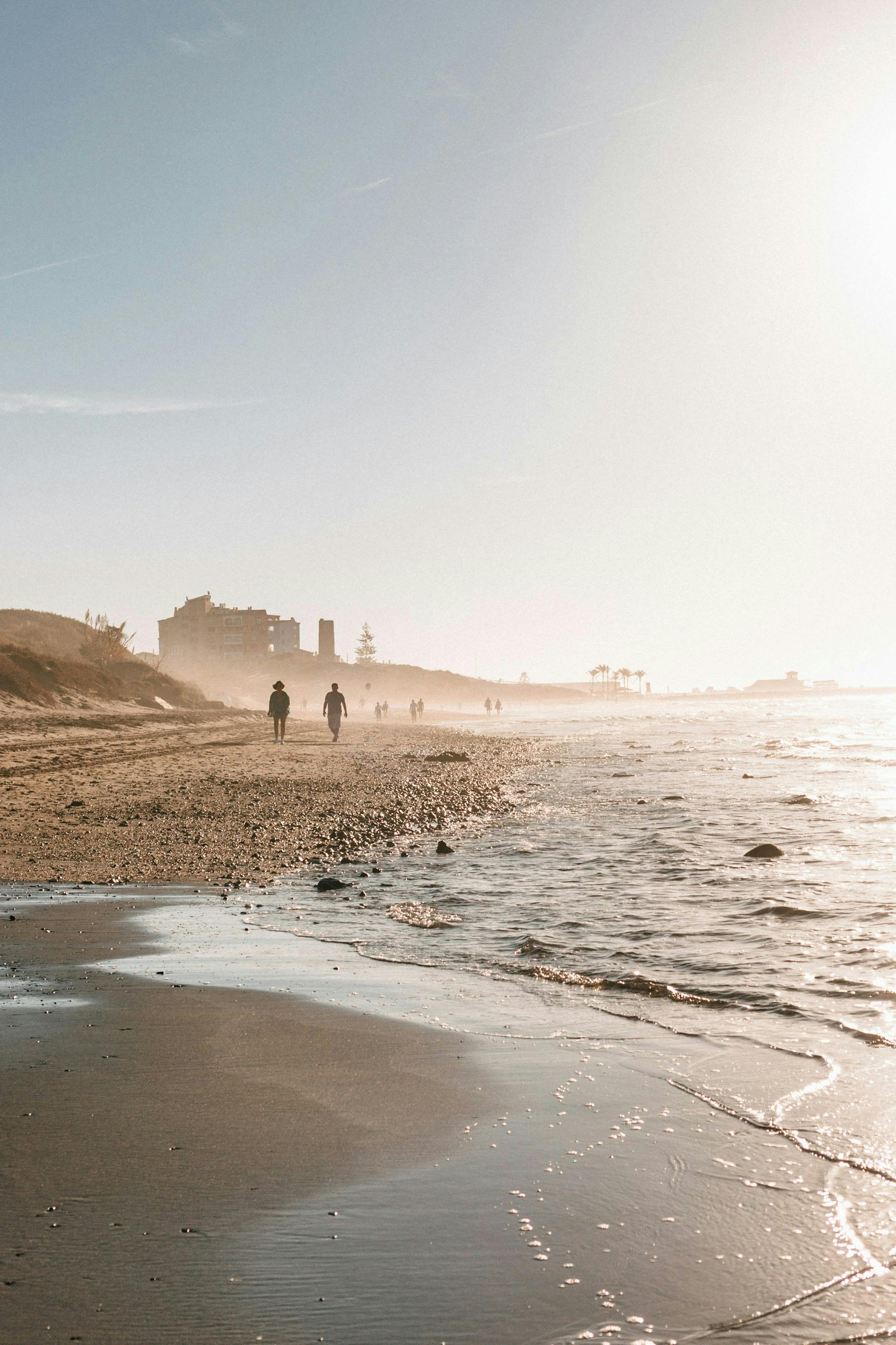 Individuals strolling on a beach in Marbella, Spain.