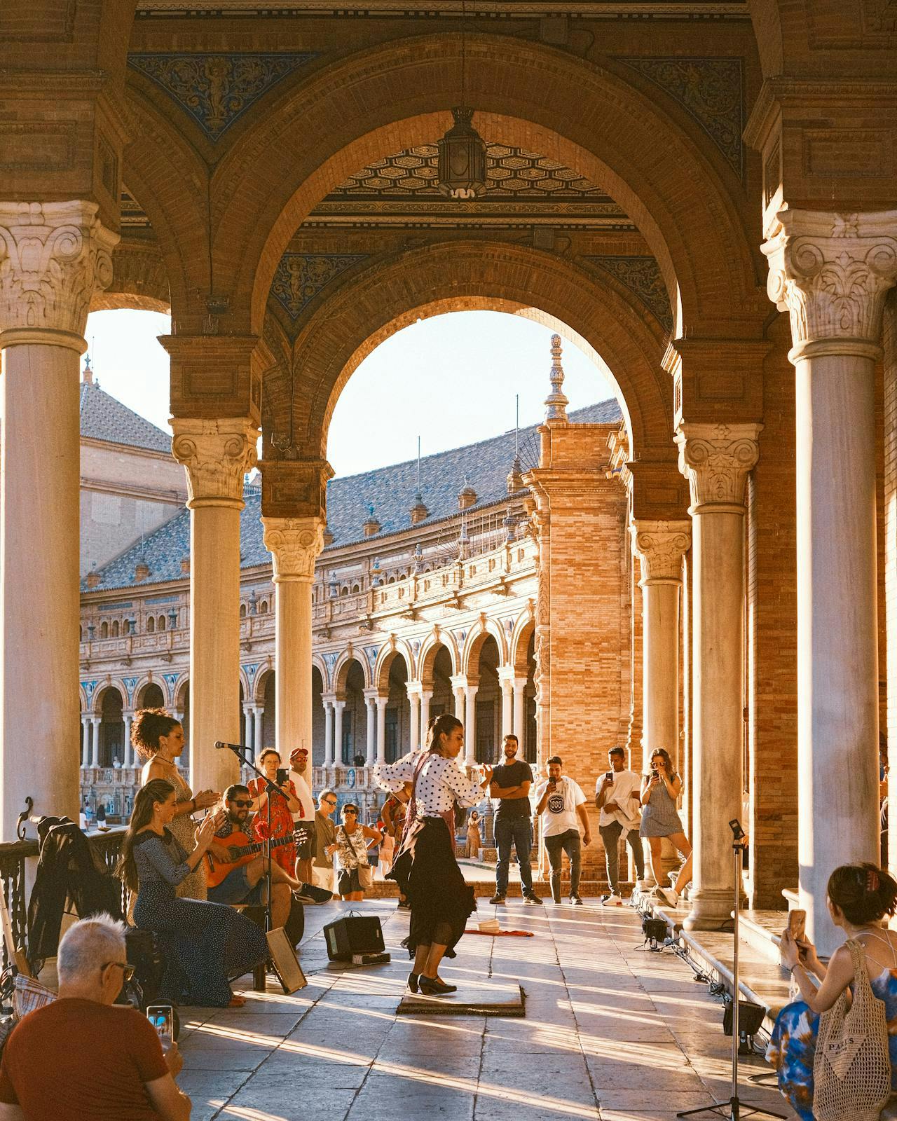 People seated in a charming outdoor courtyard adorned with arches and pillars, capturing the essence of Sevilla's architecture.