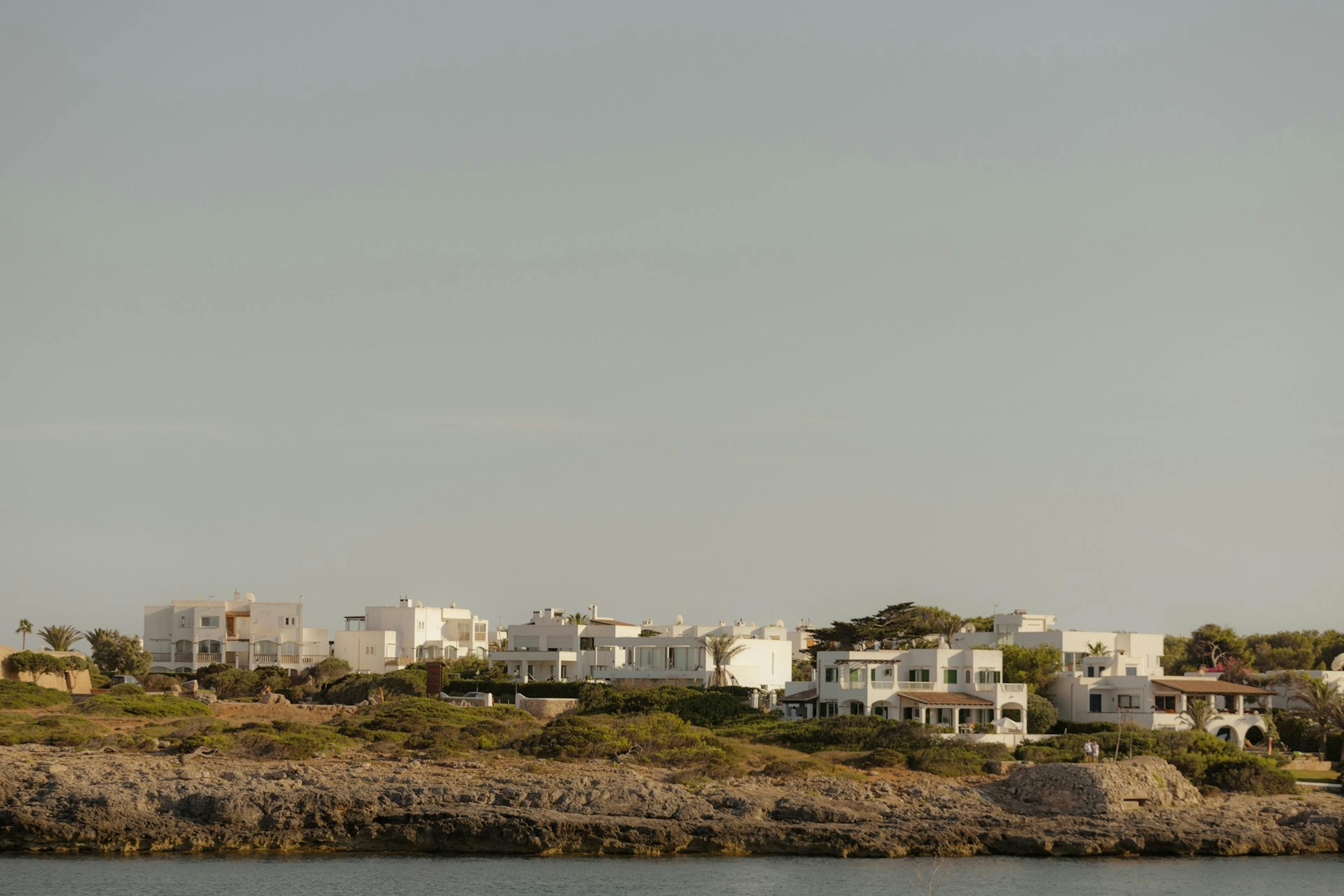 A scenic view of Mallorca's beach, featuring sandy shores and charming houses lining the coastline.