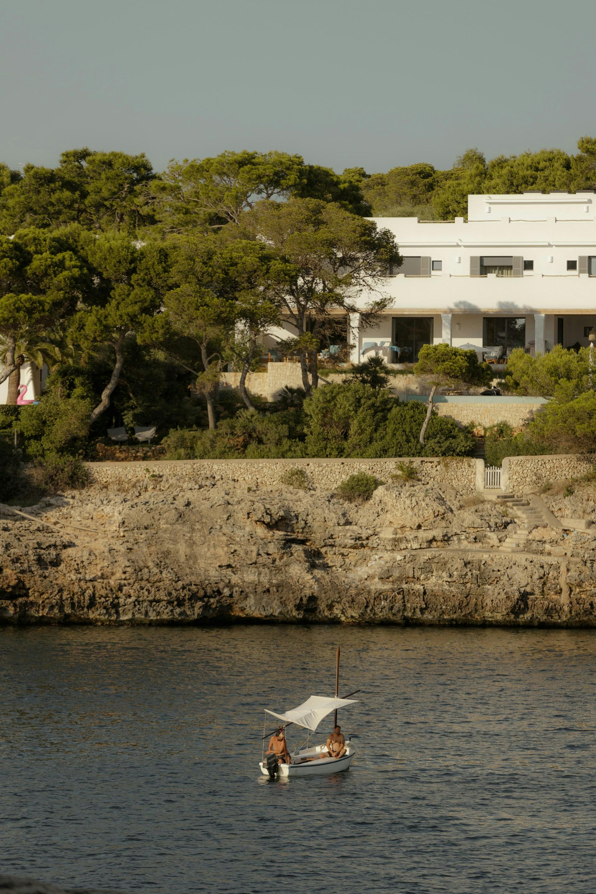 A serene body of water reflecting the clear sky, surrounded by the picturesque landscape of Mallorca.