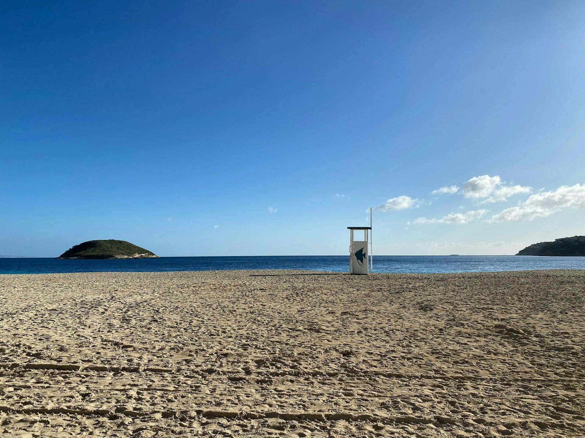 A lifeguard tower stands on a sandy beach in Magaluf, Mallorca, overlooking the clear blue waters of the Mediterranean Sea.