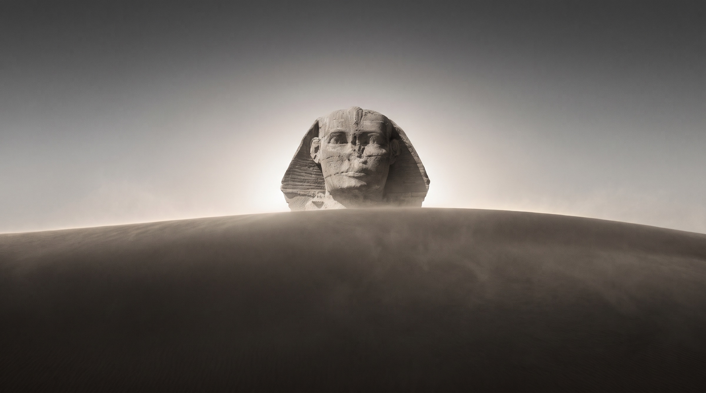 The Sphinx rising over a dune at dawn