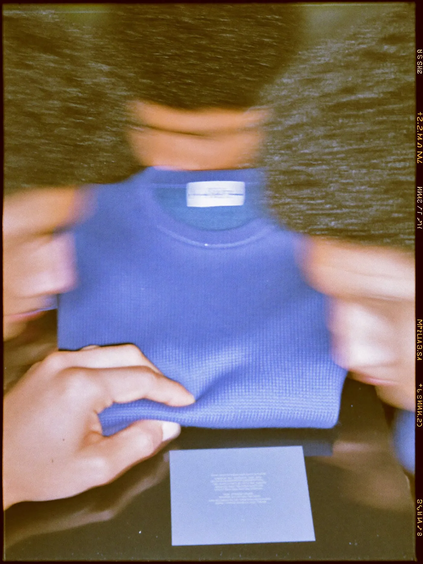 A navy sweater beside a grey card under a camera on a copy stand