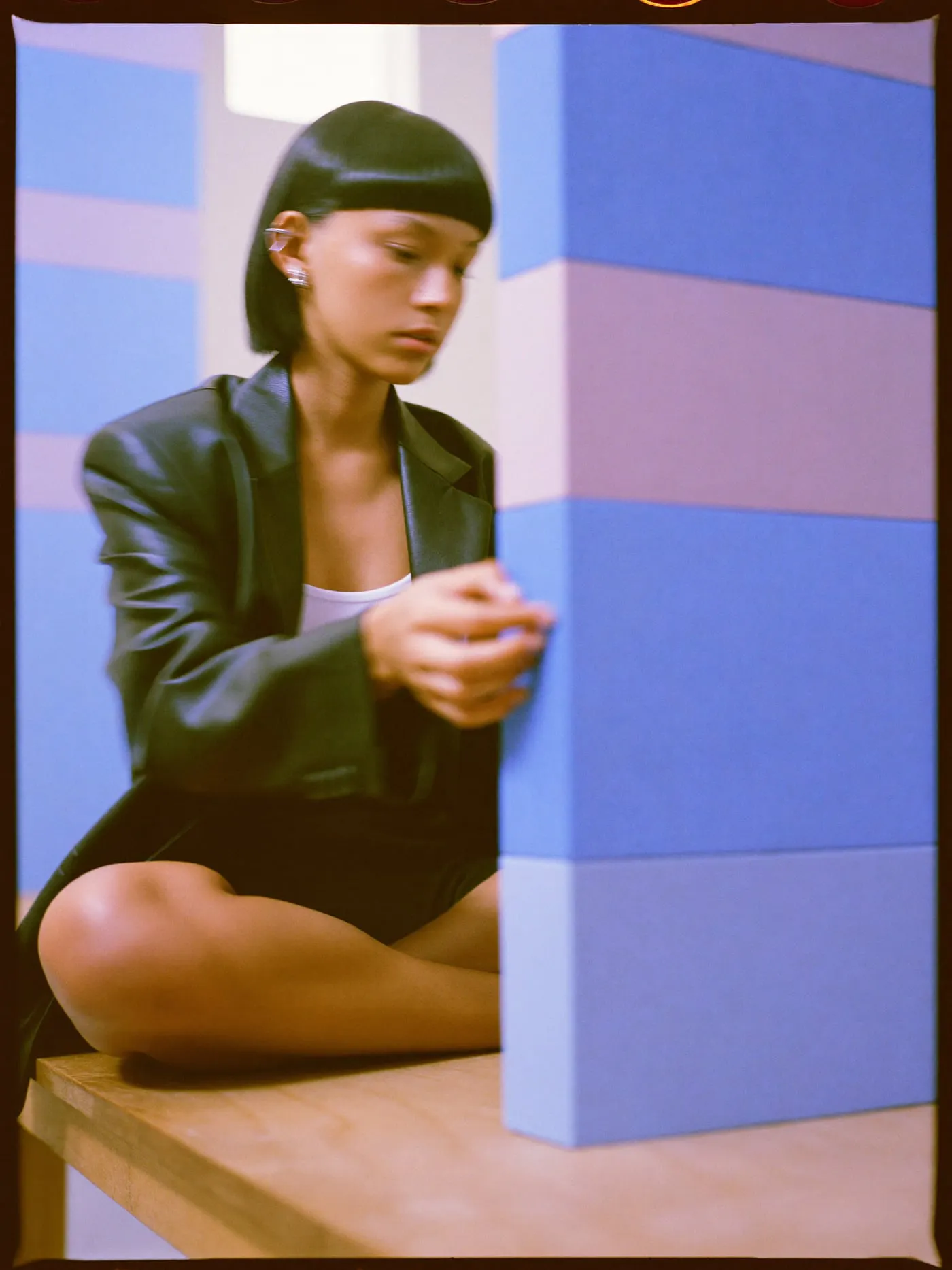 A woman with a black bob sliding a lilac block into a tall stack of coloured blocks