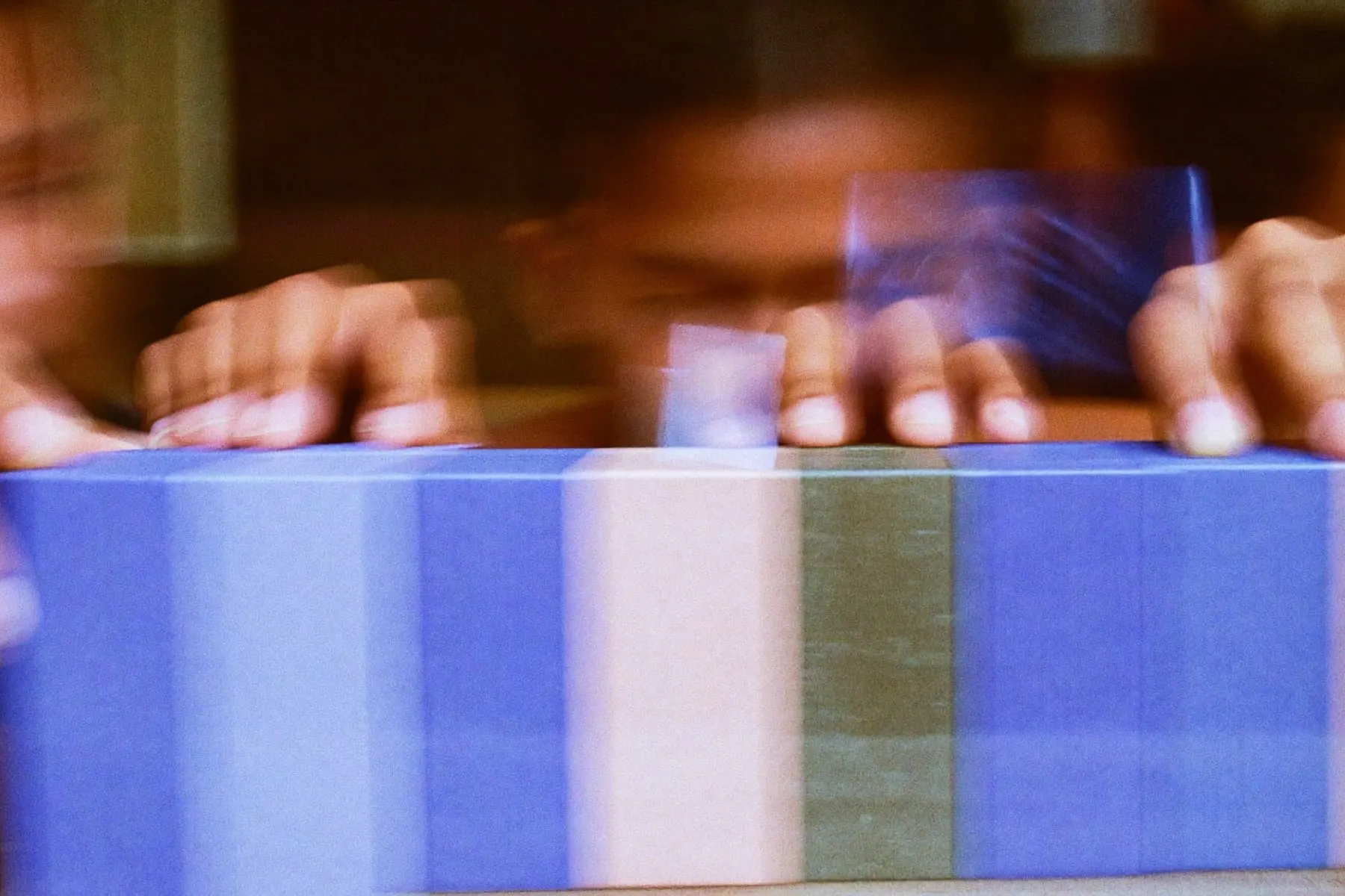 Hands placing small coloured wooden blocks in a row on a wooden table