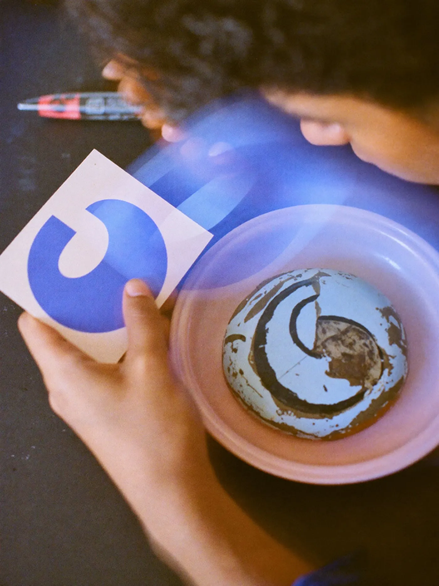 A clean new round symbol on a card next to an old chipped plate with a rough version of it