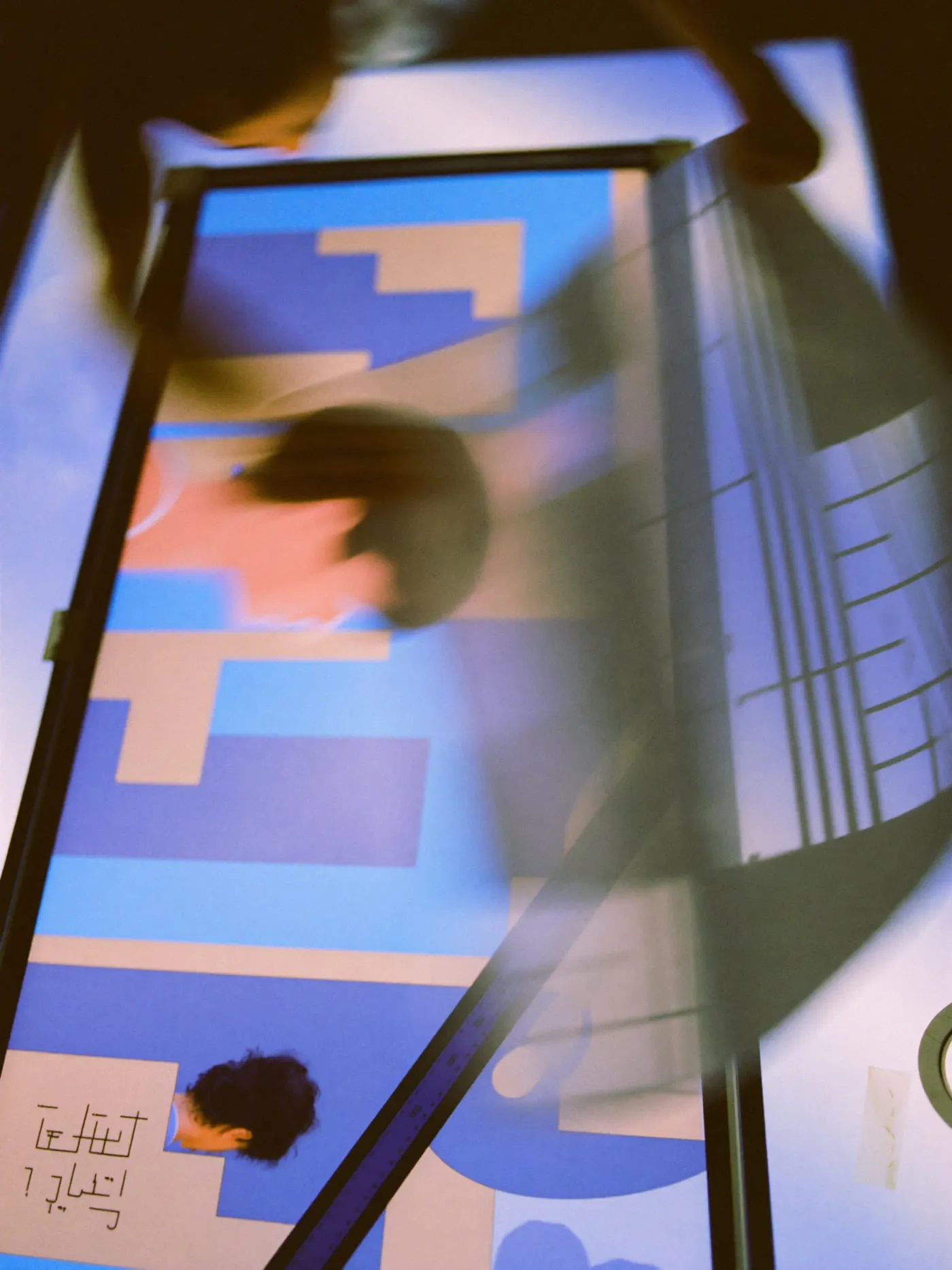Hands flipping a translucent layout sheet of abstract blocks over on a light table