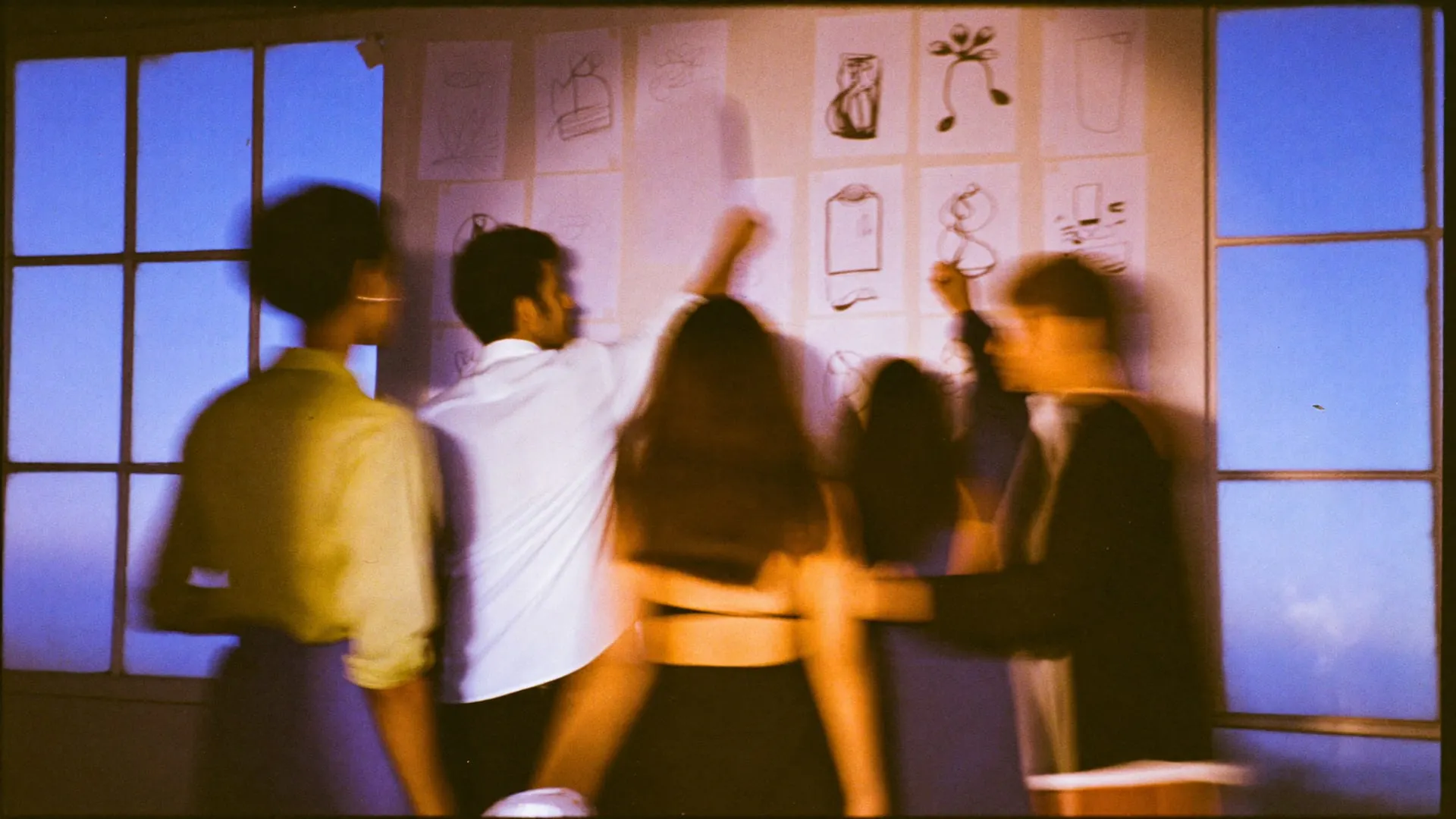 Colleagues gathered around a wall of pinned sketches in a Cairo studio