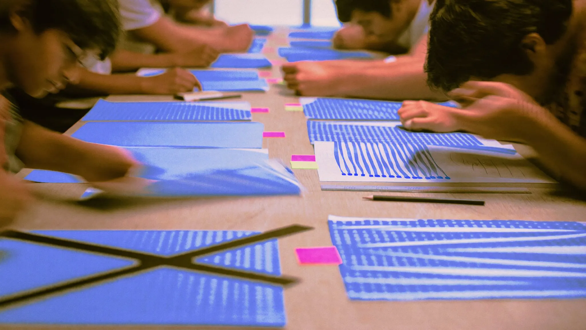Grid paper sheets with hand drawn bar shapes laid across a long meeting table