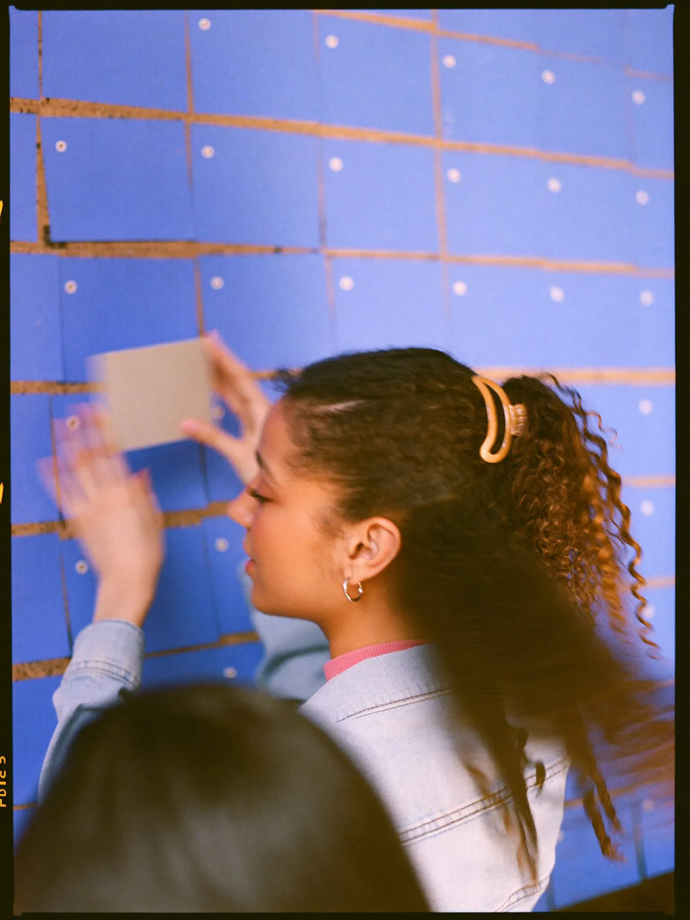 A young woman pinning a blank card onto a wall of planning cards