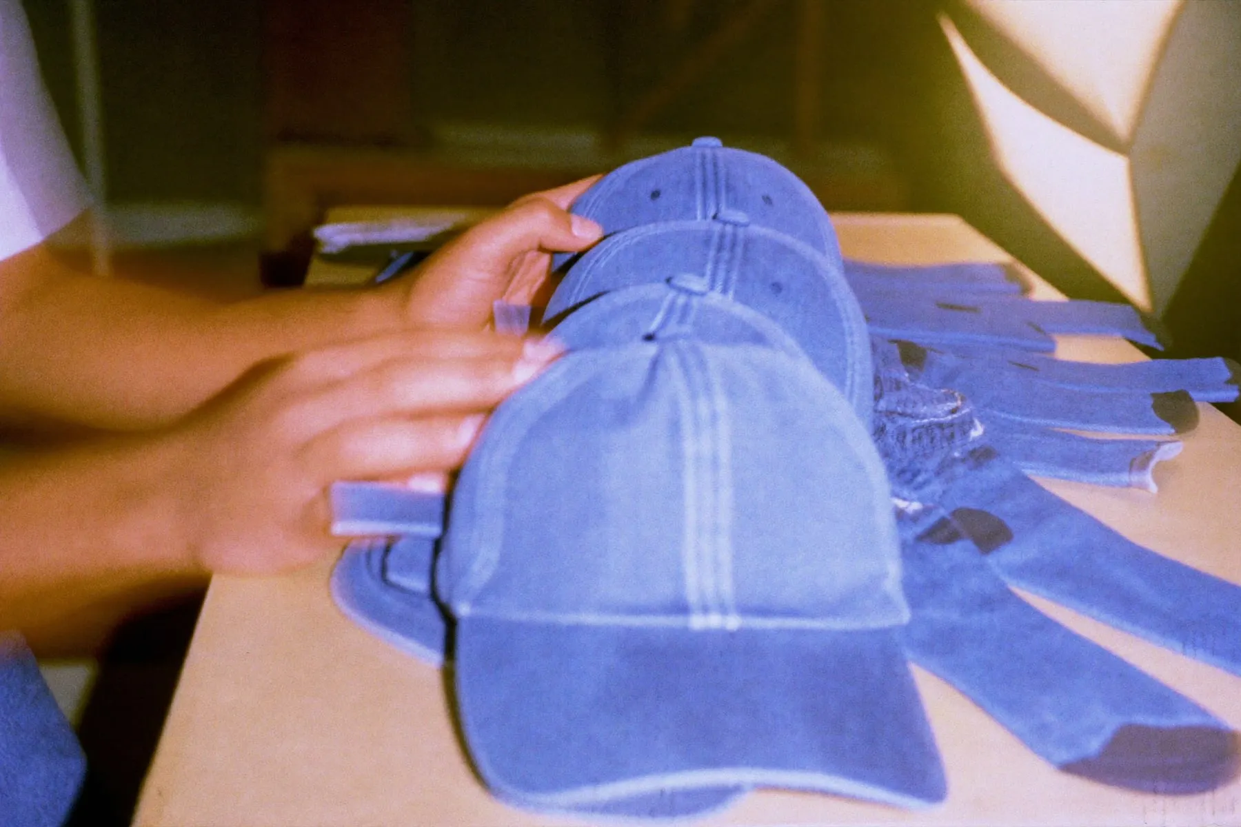 Hands laying out plain denim caps and socks on a table for a product photo