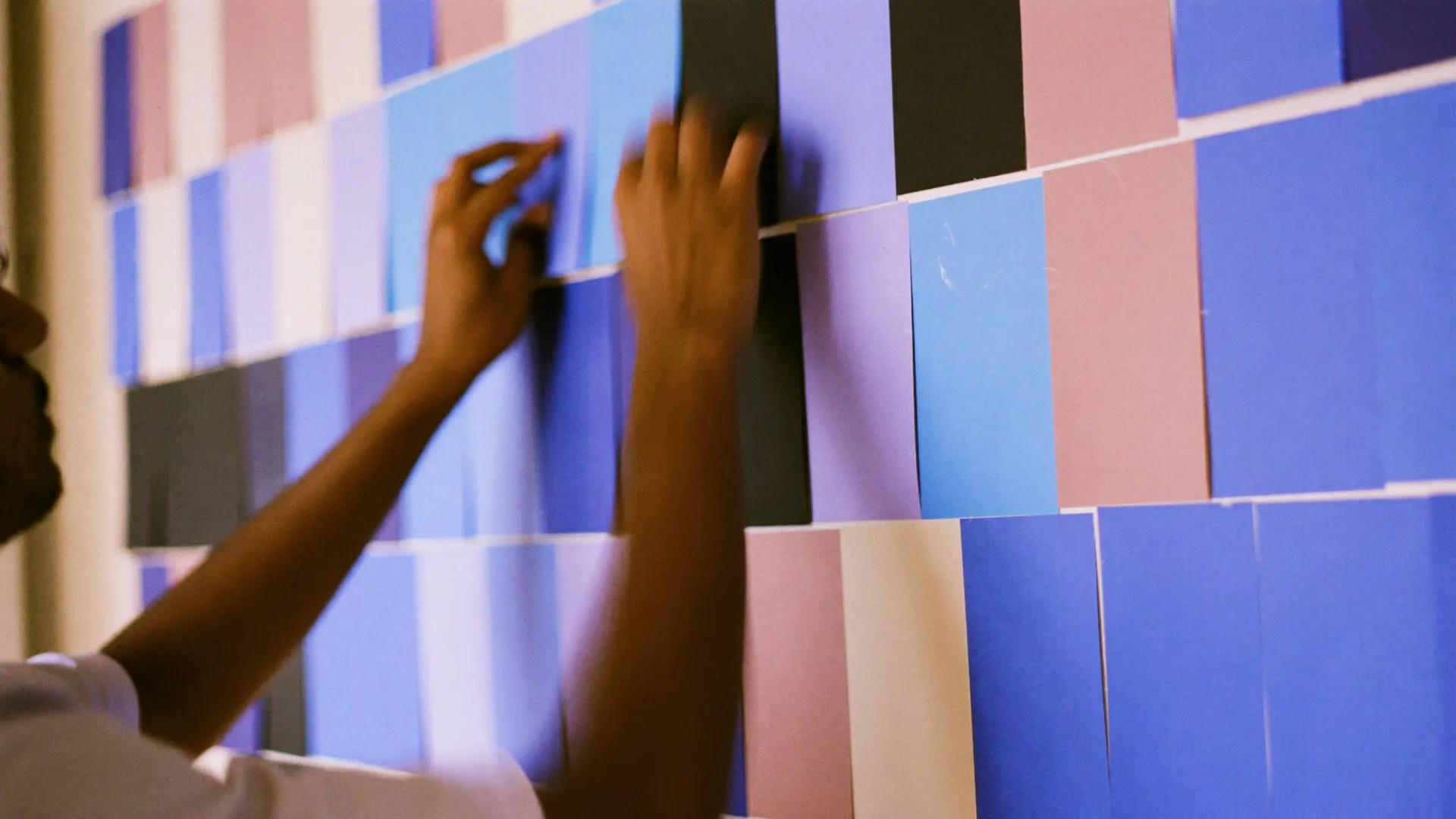 Hands moving coloured cards across a wall planner