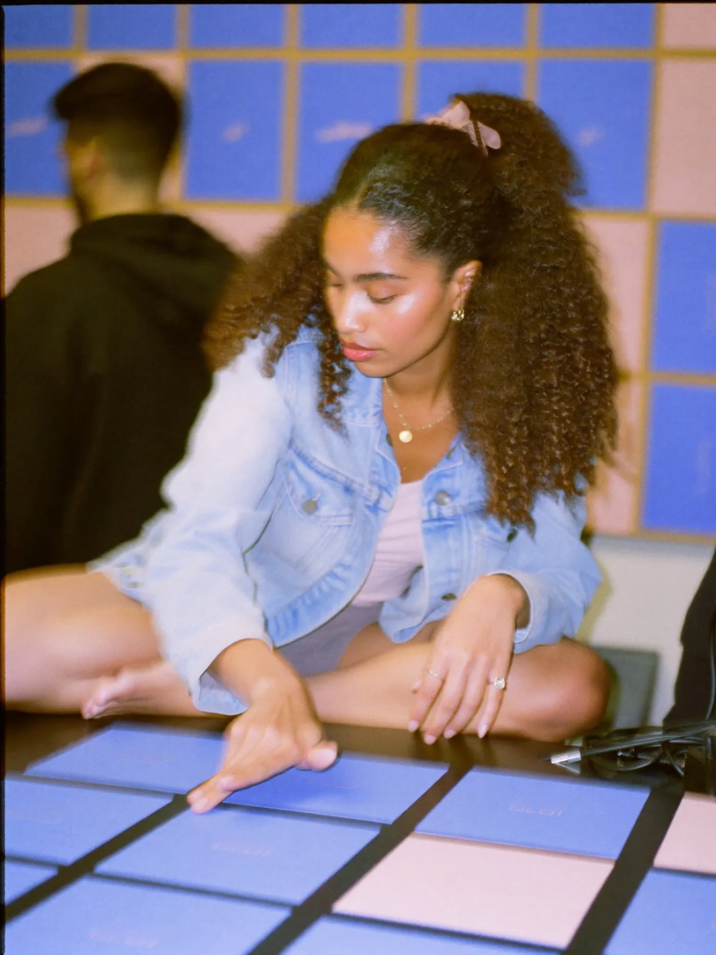 Young woman sitting on a studio desk arranging blue and pink cards beside a developer