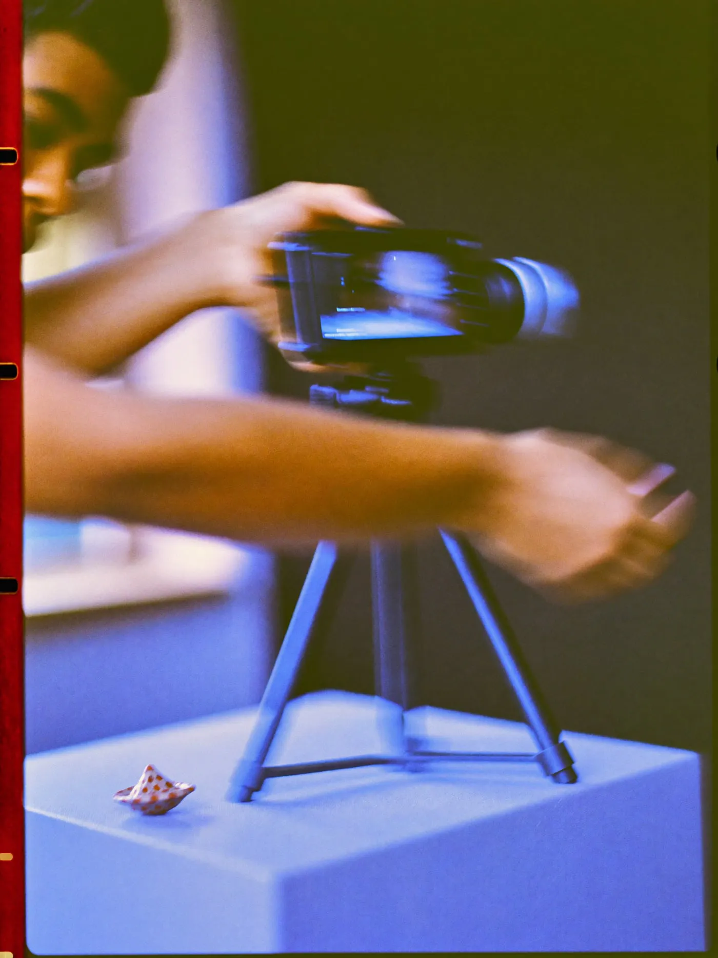 Hands rotating a camera on a tripod from horizontal to vertical in front of a product