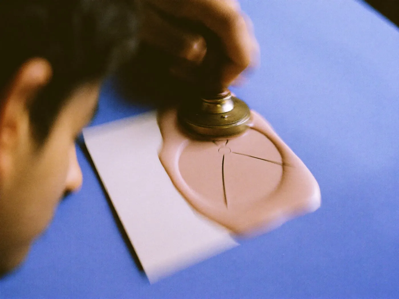 A brass stamp leaving a simple round symbol in blush sealing wax