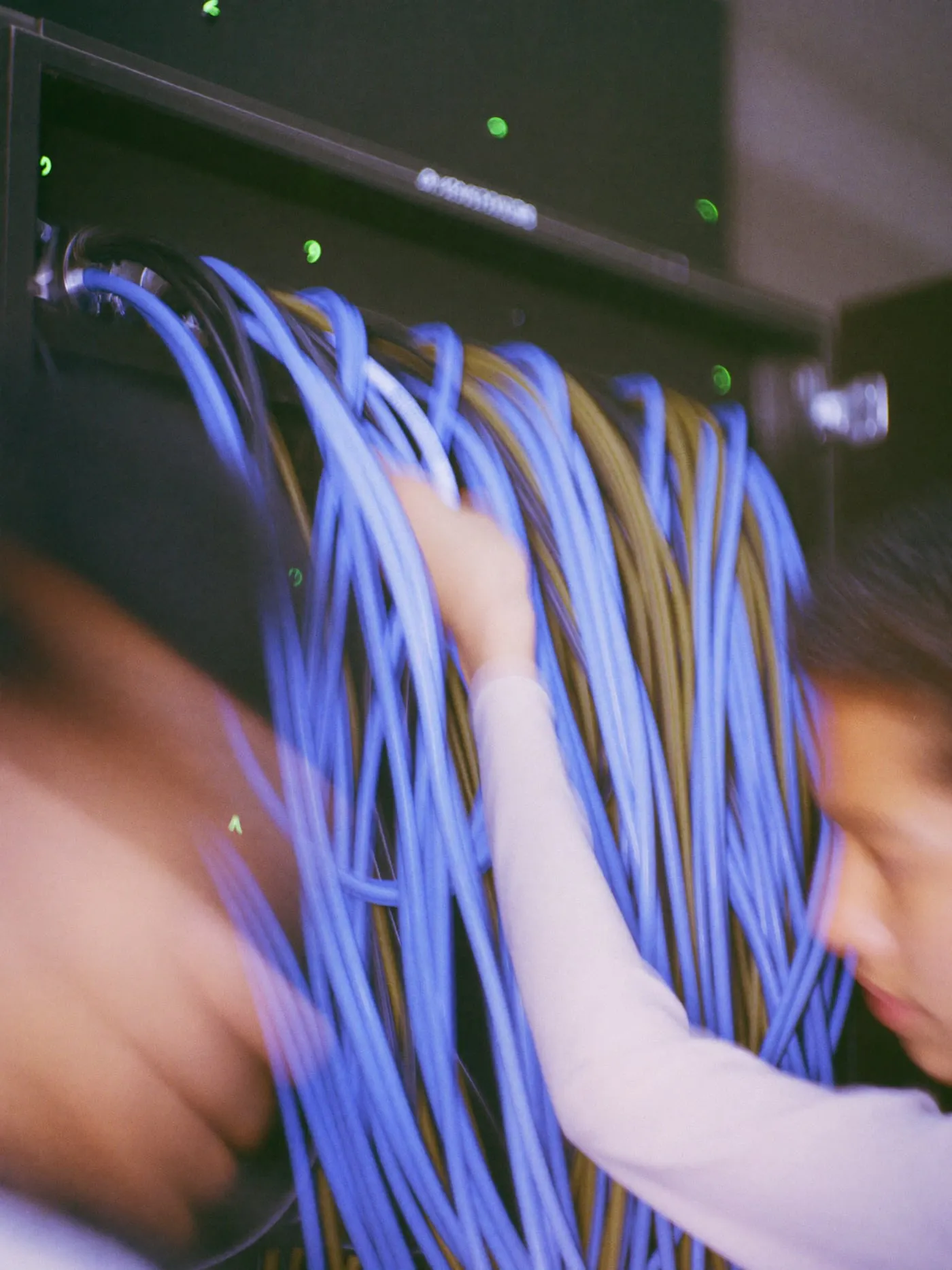 A hand reseating a patch cable in a network switch full of looping cables