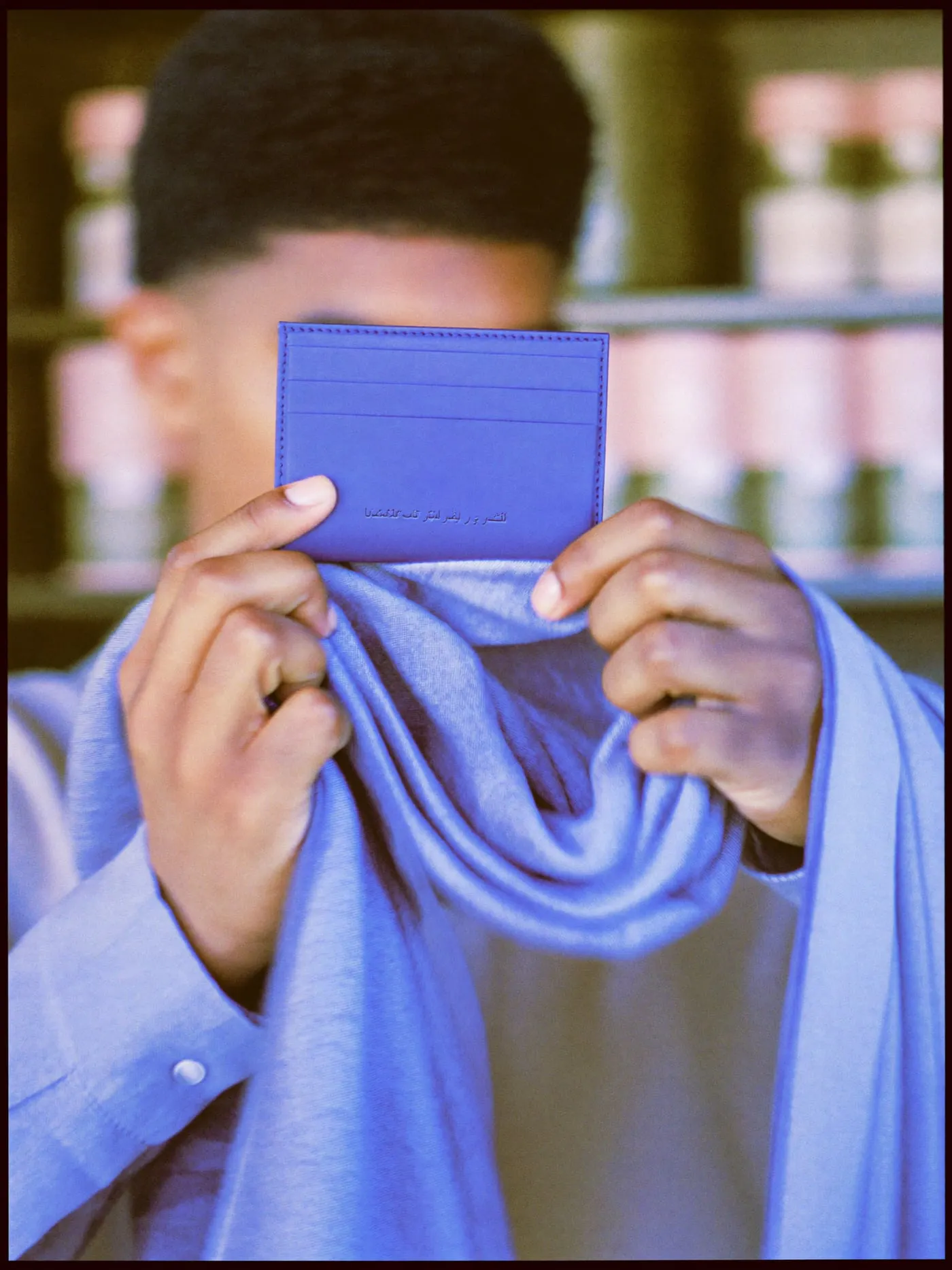 Hands turning a leather card holder and a folded linen scarf in window light