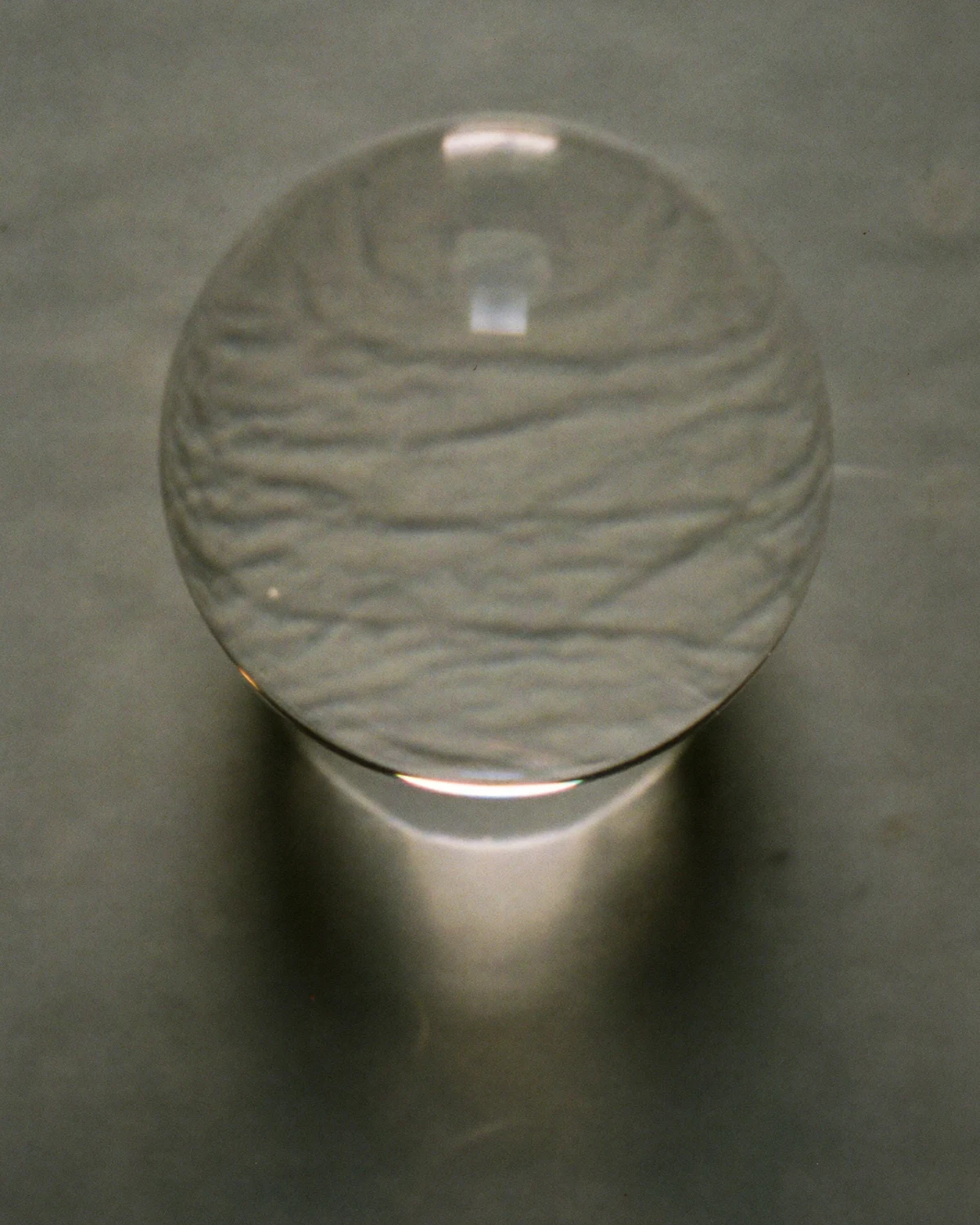 A clear glass lens resting on grey stone