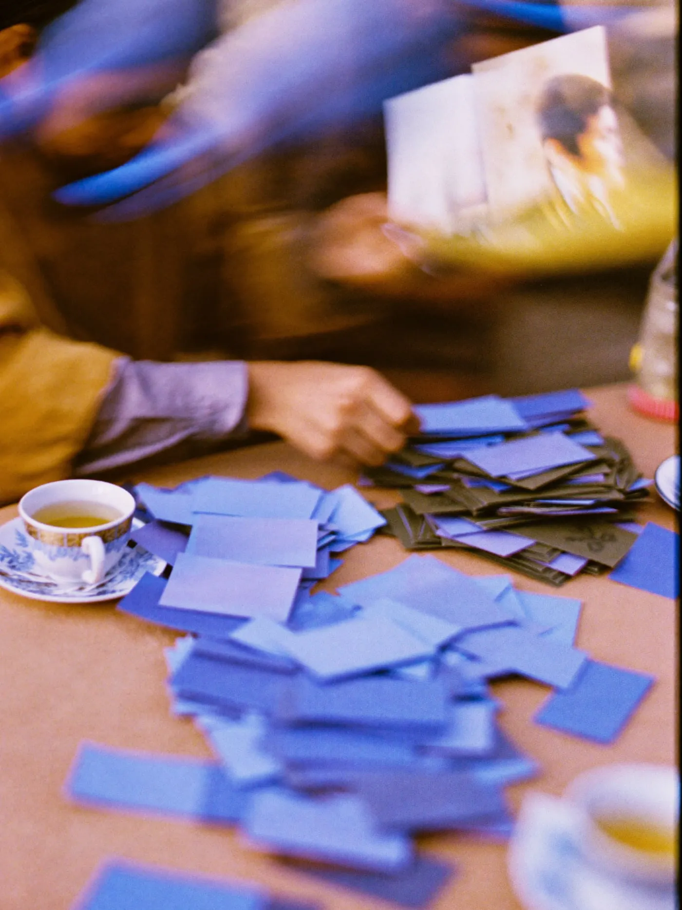 Hands sorting small colour swatch cards into three piles on a table