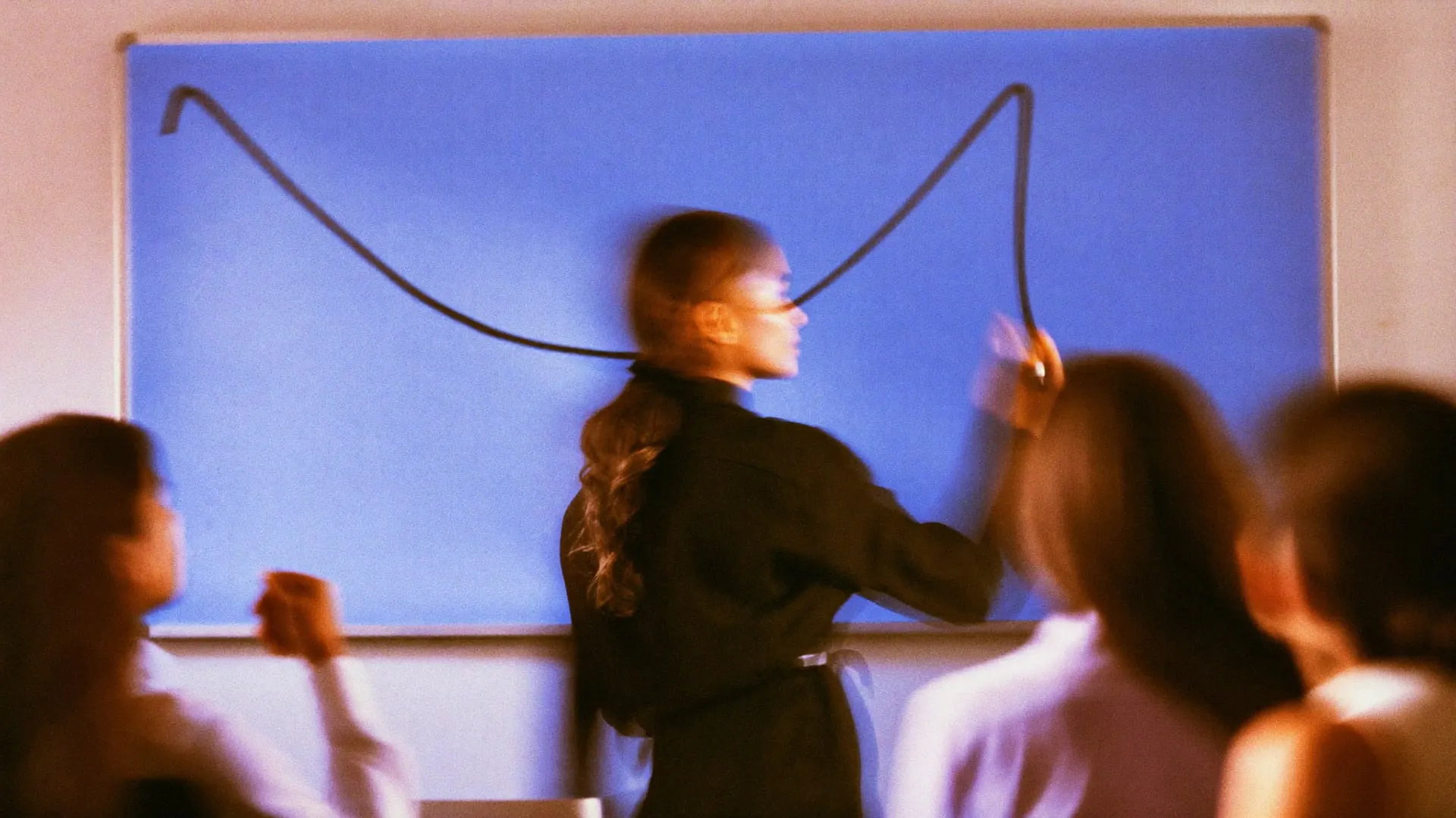 A strategist drawing a line on a whiteboard while two colleagues watch