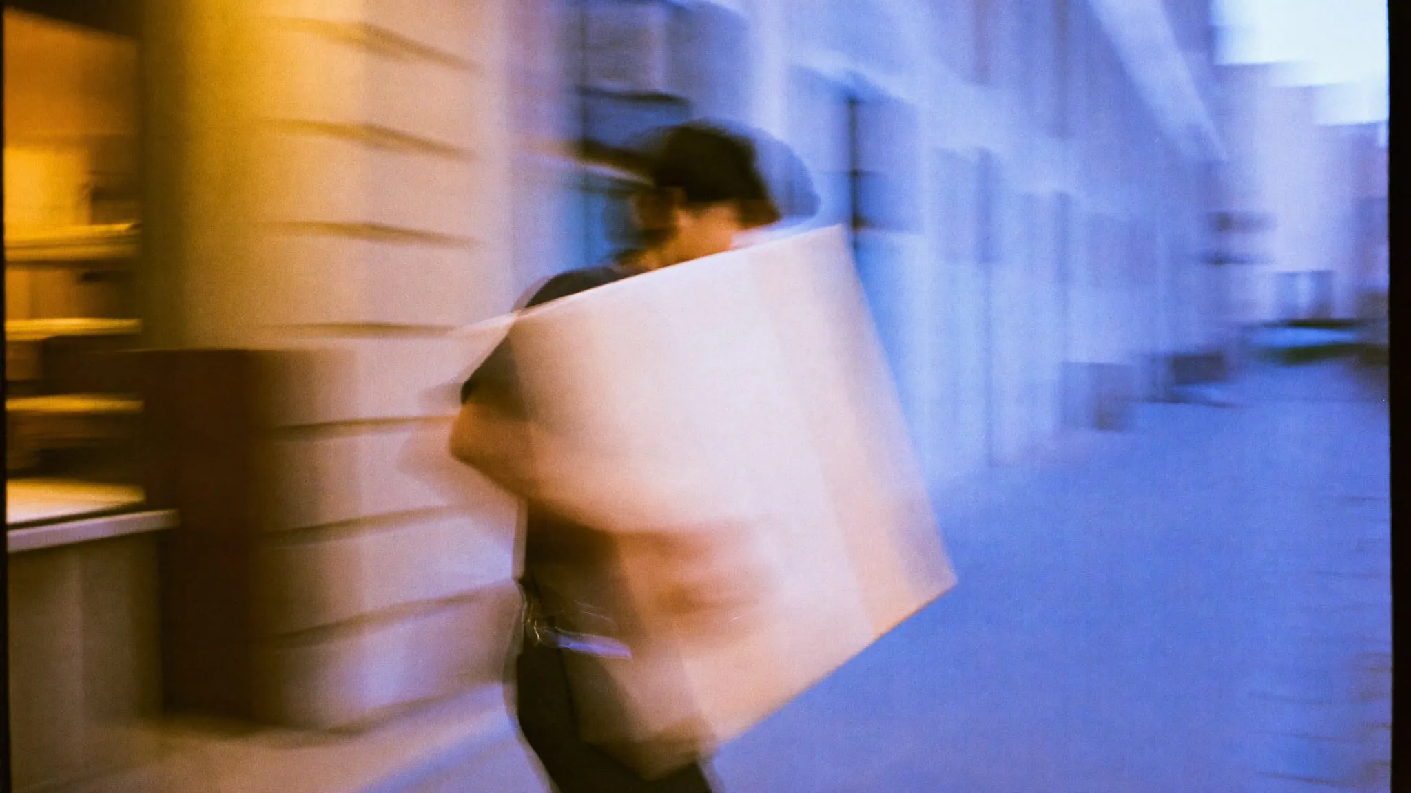 A man walking fast through a downtown Cairo colonnade carrying a large wrapped package