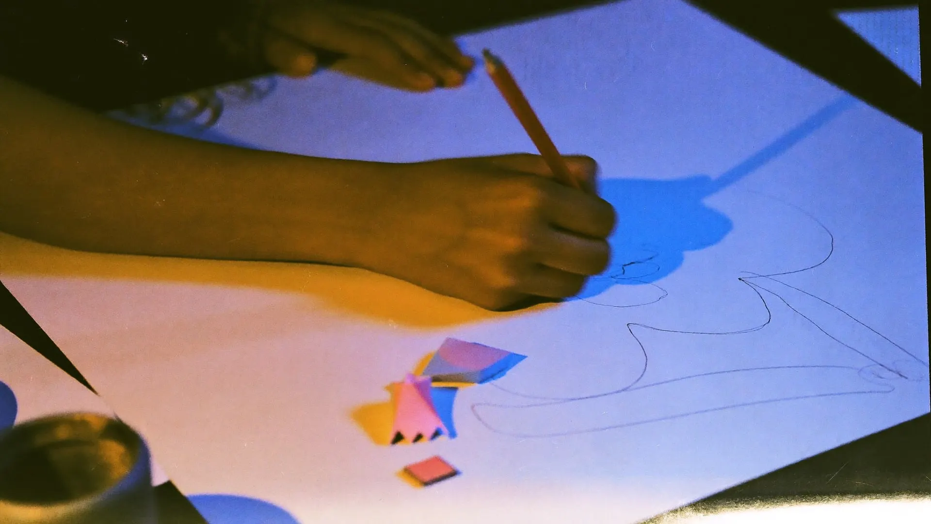 A designer sketching shapes on a large sheet next to colour swatches