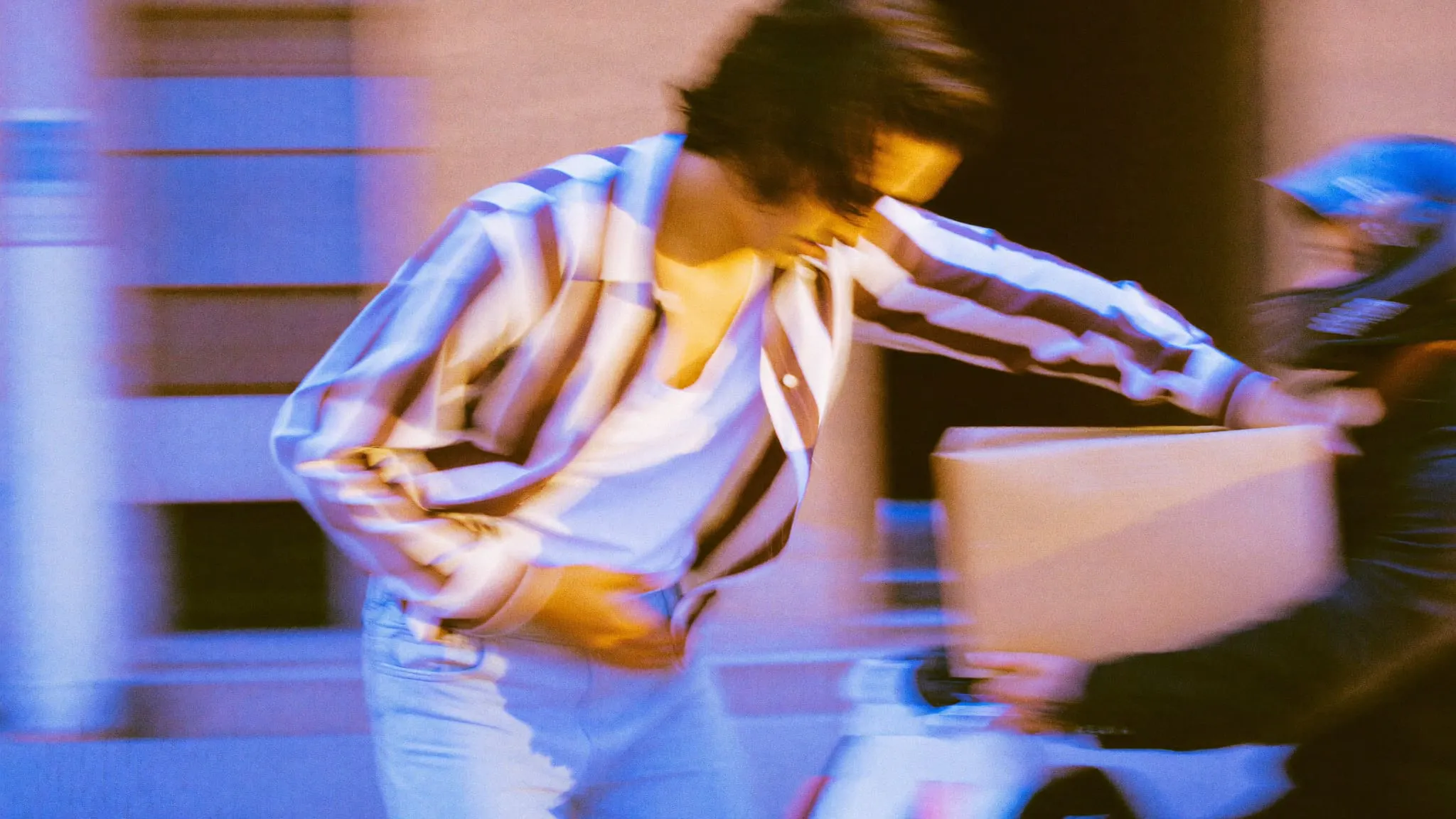 A young man with long wavy hair taking a kraft parcel from a motorbike courier