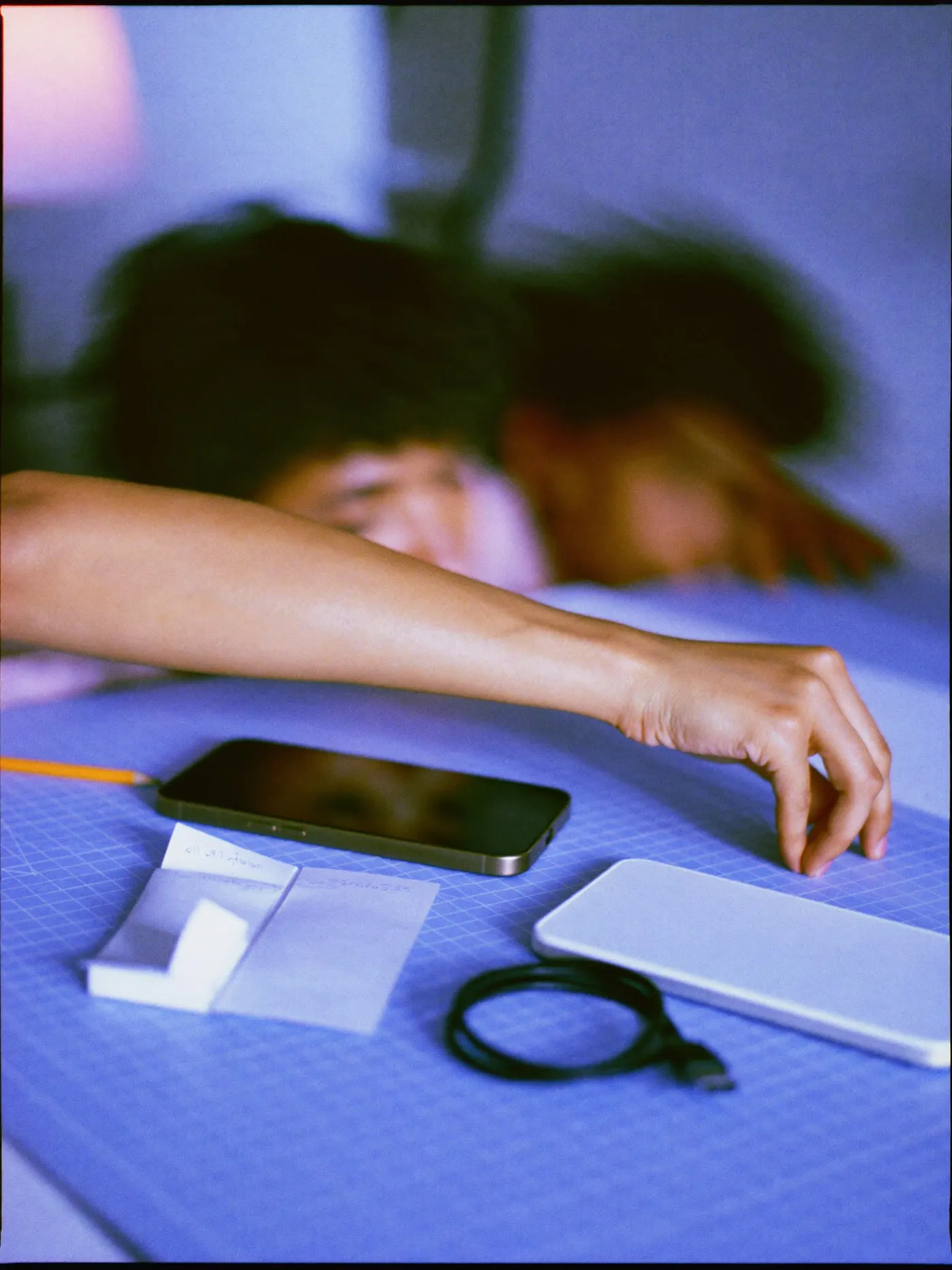 Two phones face down on a cutting mat beside a cable and a paper prototype