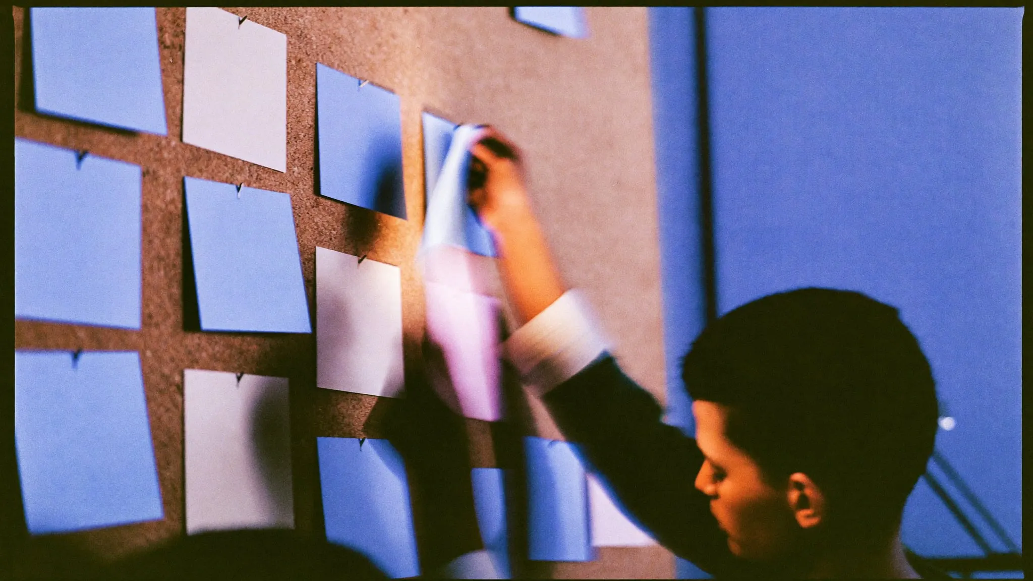 A designer pinning colour cards in a grid on a cork wall