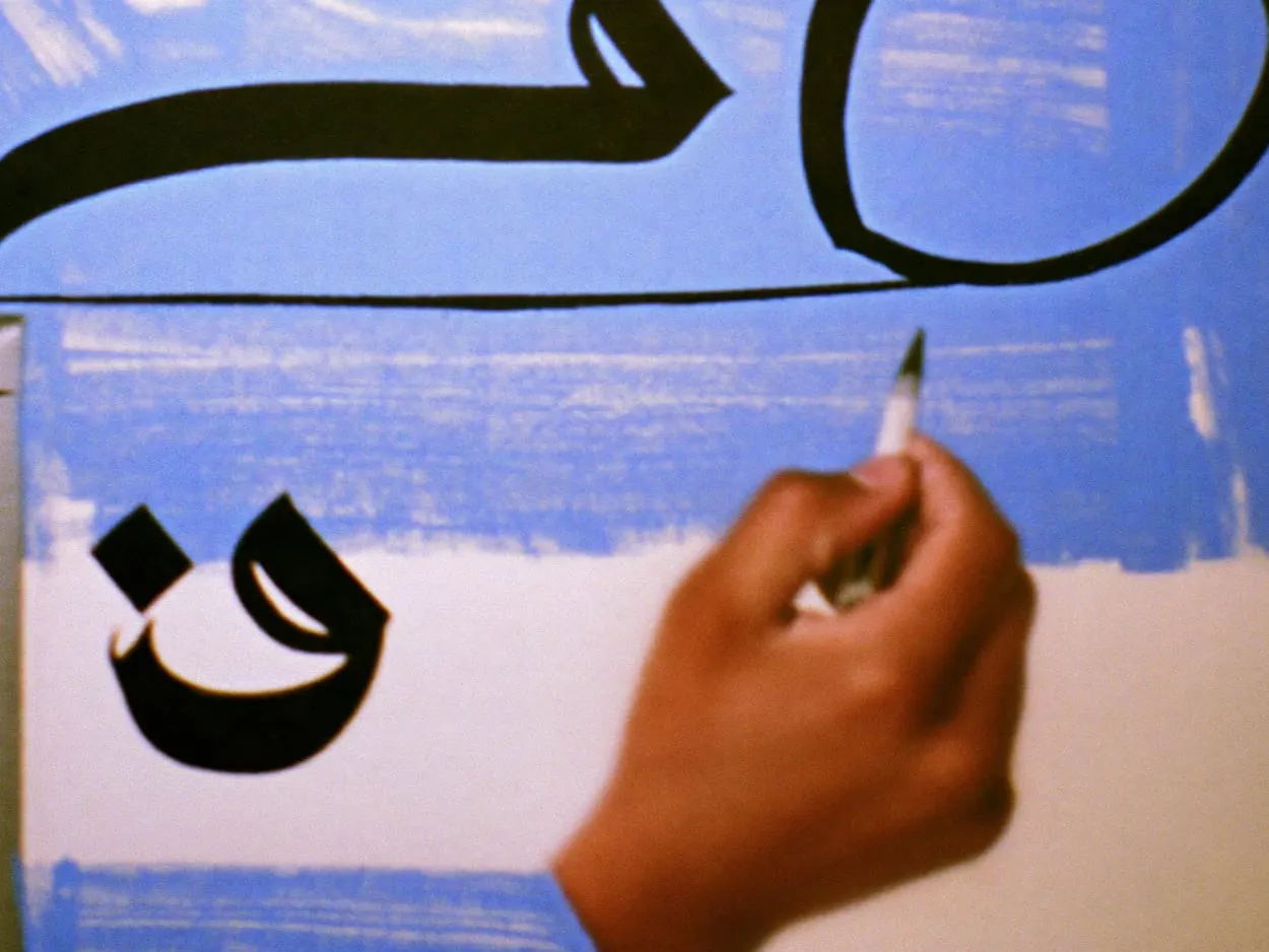 A hand inking a custom brush shape over pencil guide lines