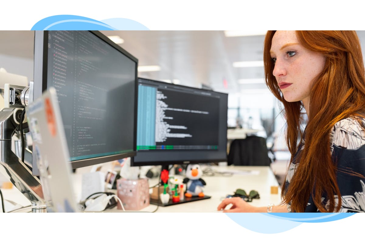 a lady engineer working at a desk with three monitors