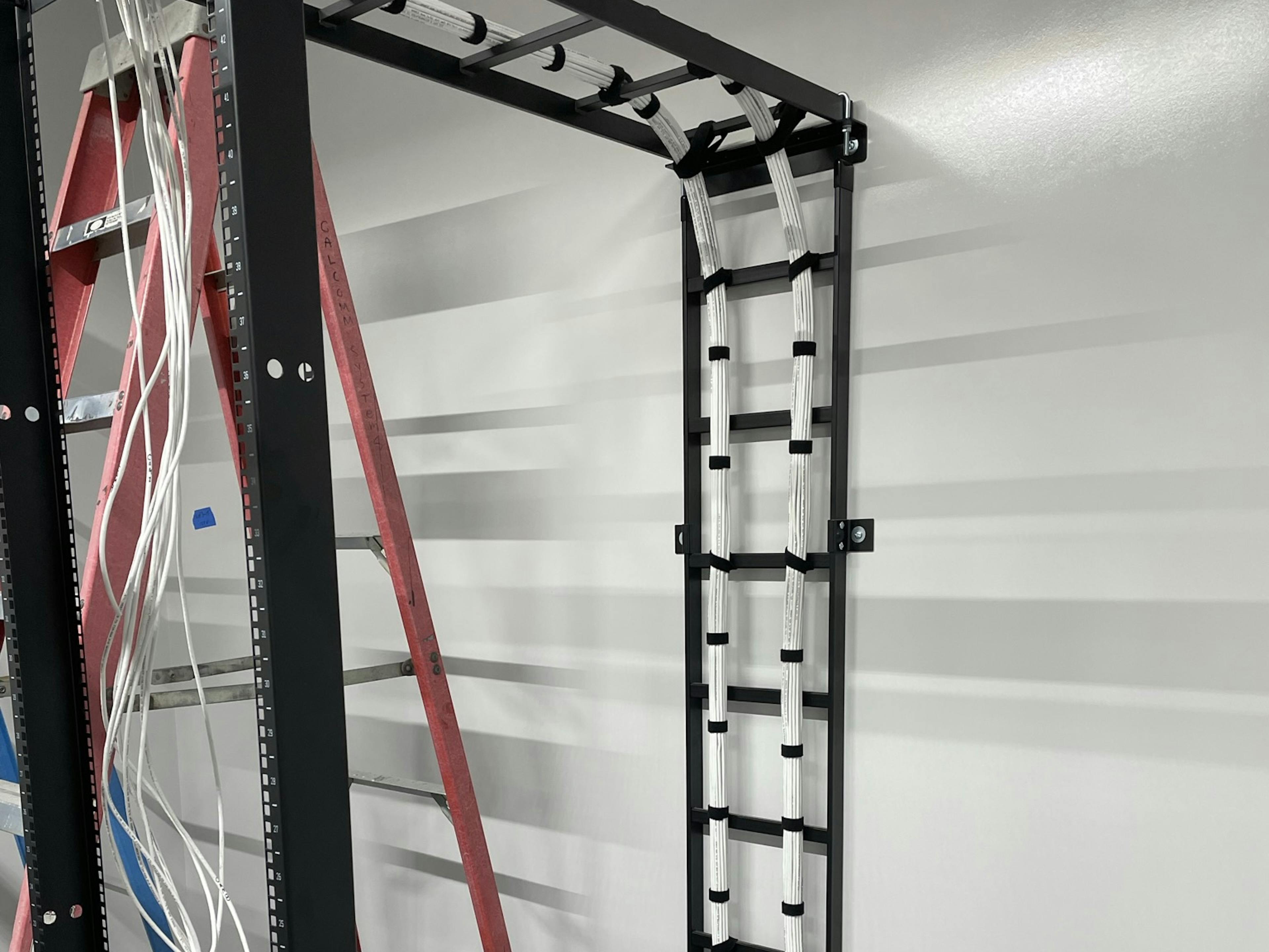 cables being installed into a server rack from conduit in the floor