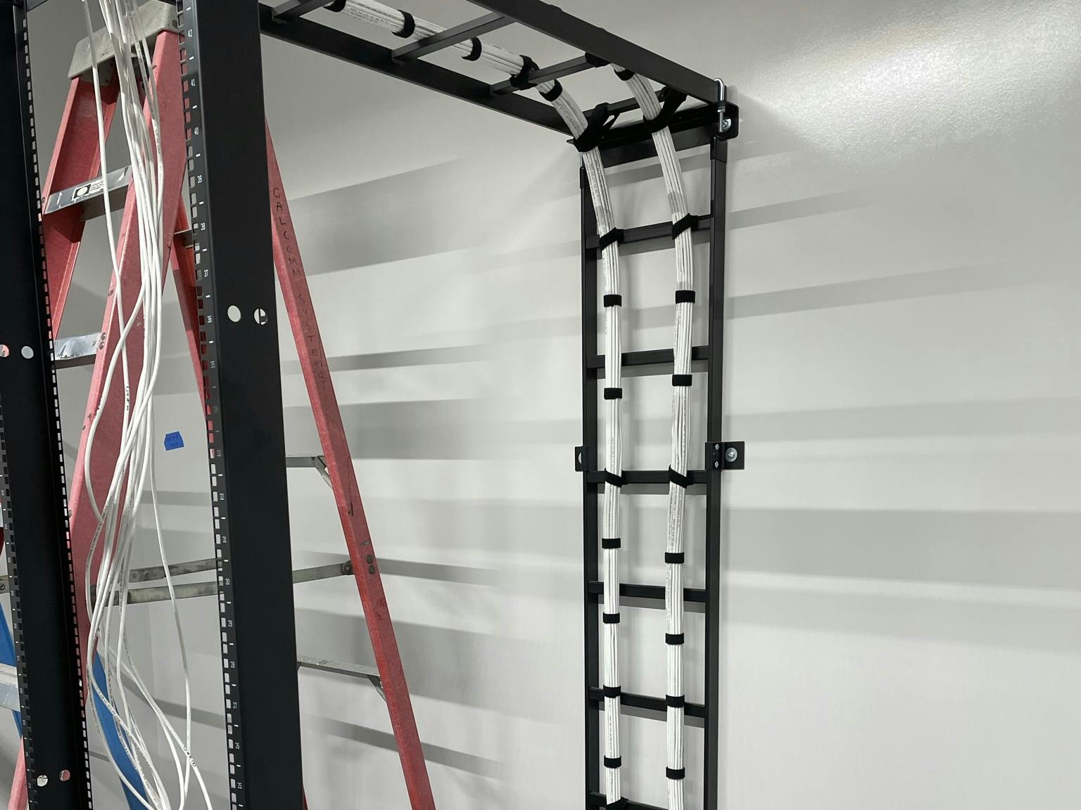 cables being installed into a server rack from conduit in the floor