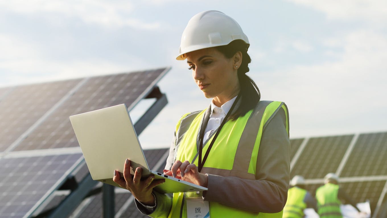 Female engineer works on laptop at a solar farm