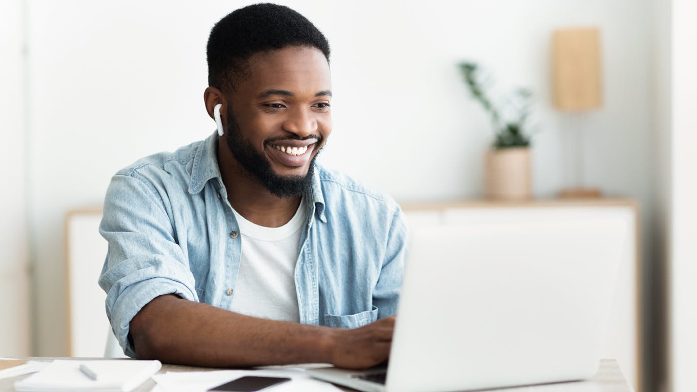 Smiling man at his laptop attending virtual mindfulness training